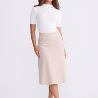 Model wearing Oriane Skirt in beige, back view on white background