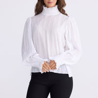 Model wearing Isolde Blouse in white with high neck and bishop sleeves, back view on white background