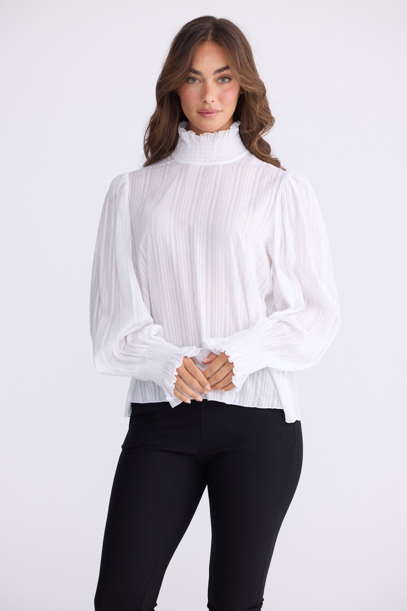 Model wearing Isolde Blouse in white with high neck and bishop sleeves, back view on white background