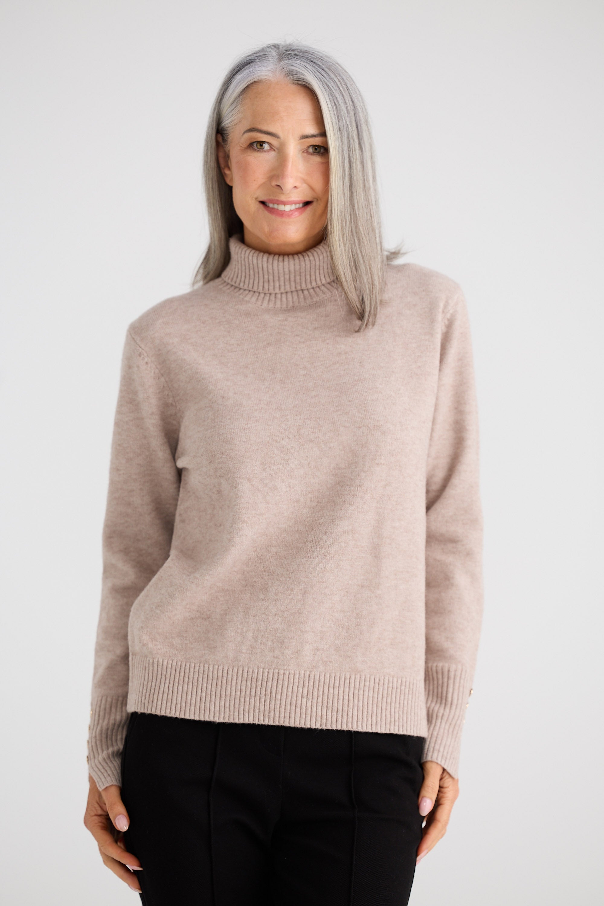 Woman wearing a beige turtleneck sweater against a white background