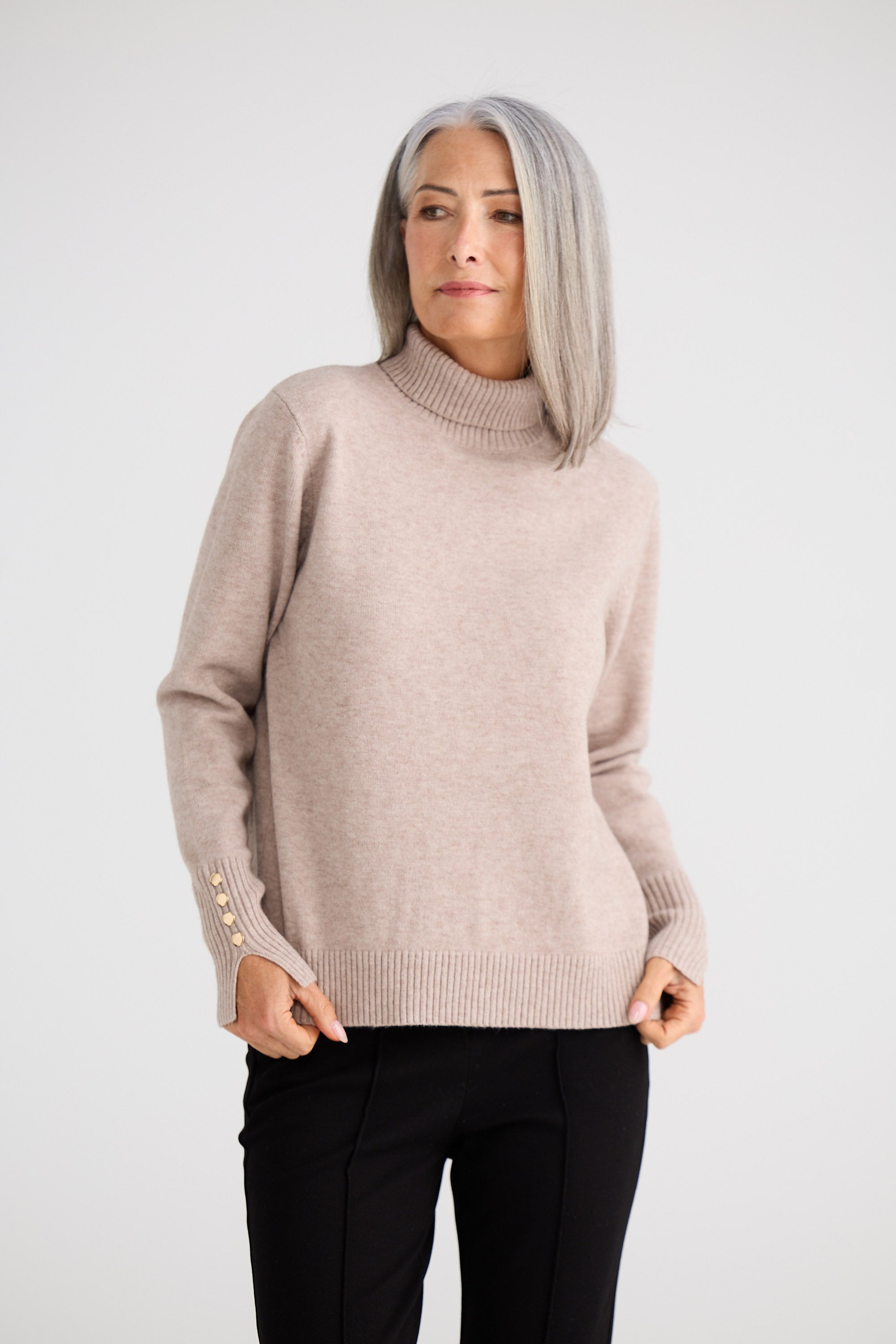 Woman wearing a beige sweater with buttons on a white background