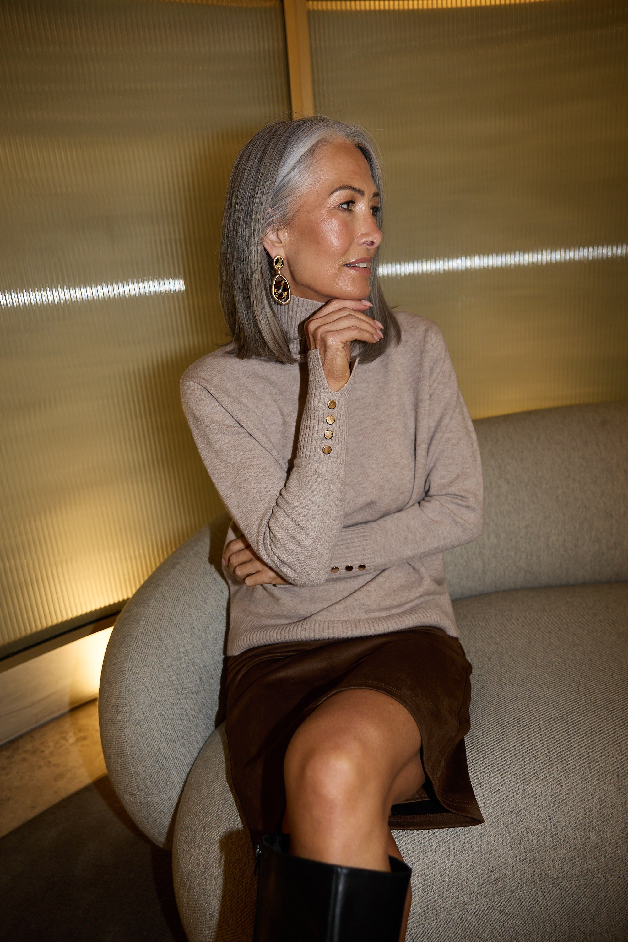 Woman sitting on a couch in a modern indoor setting