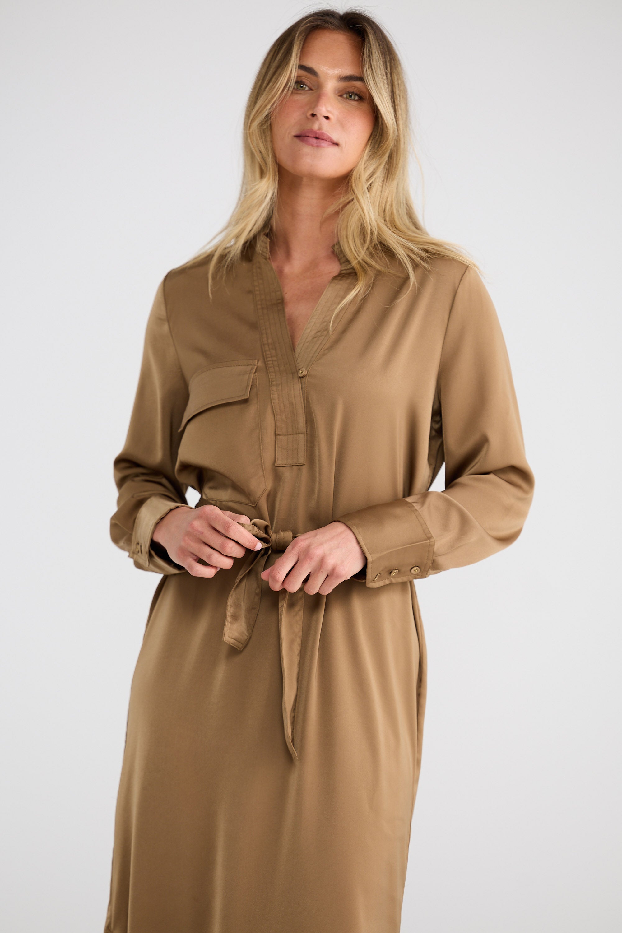 Woman wearing a long brown dress against a white background