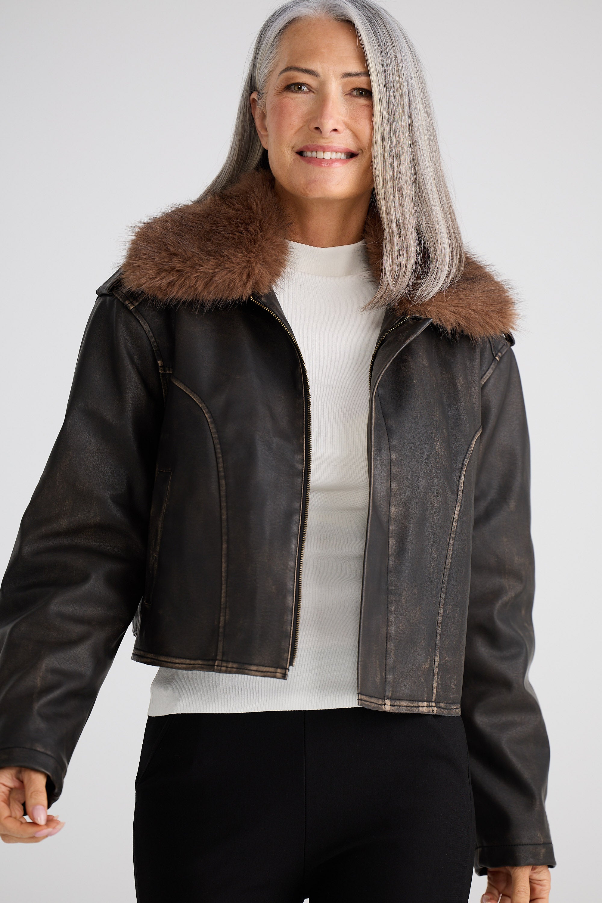 Woman wearing a black leather jacket with fur collar on a white background