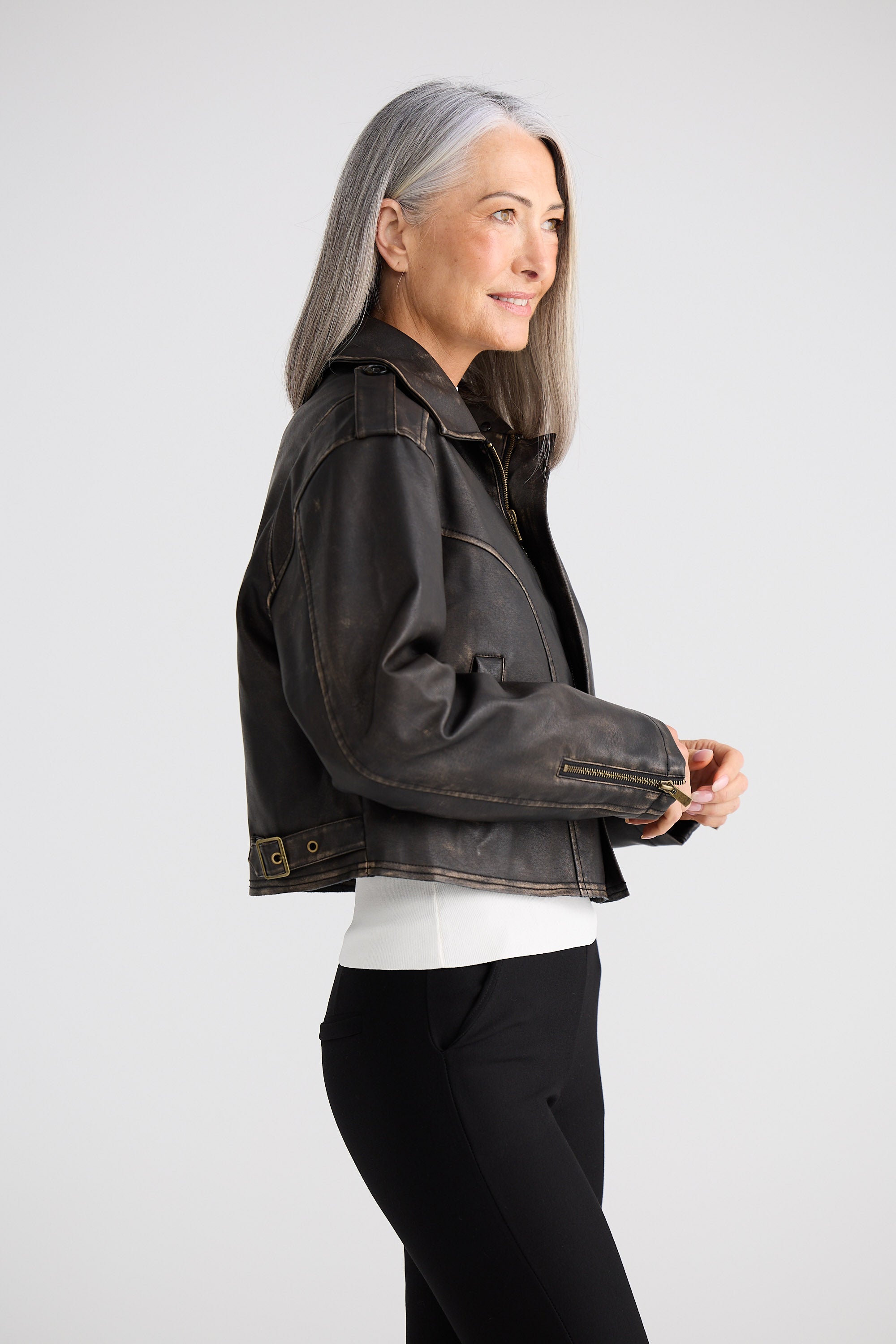 Woman wearing a dark denim jacket on a plain background