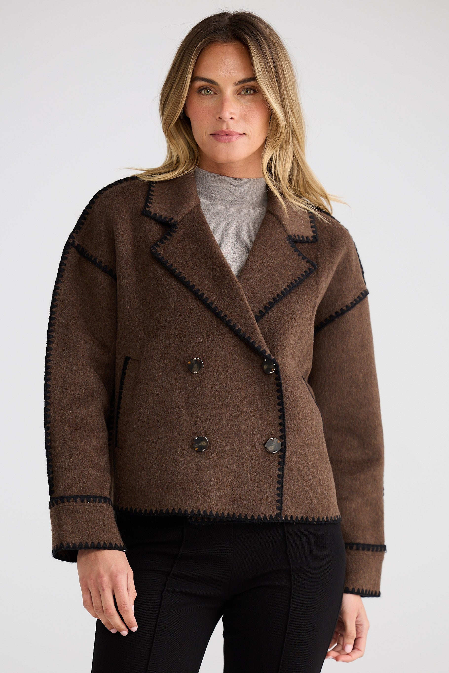 Woman wearing a brown jacket with black trim on a white background