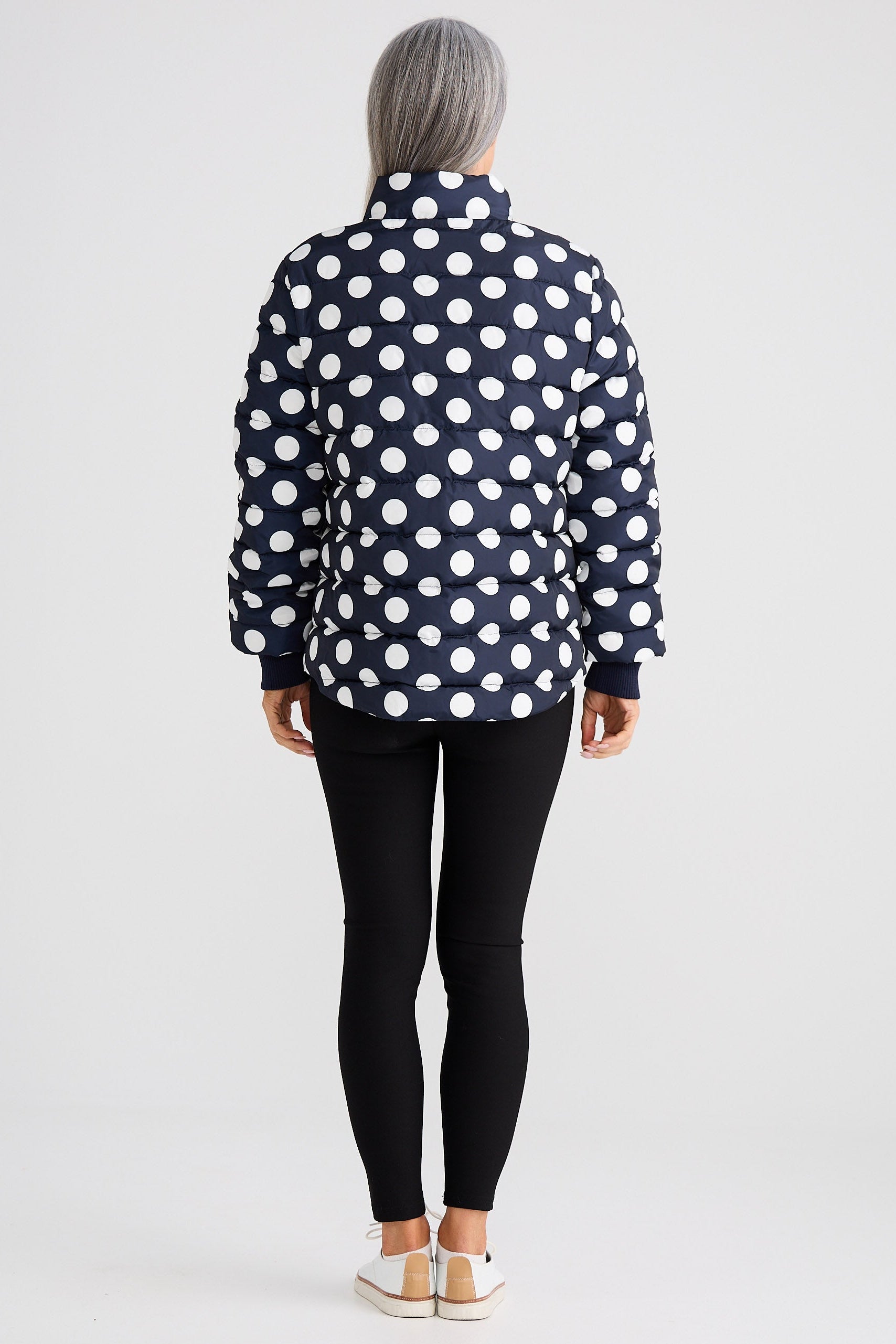 Person wearing a black polka dot shirt and black leggings on a white background