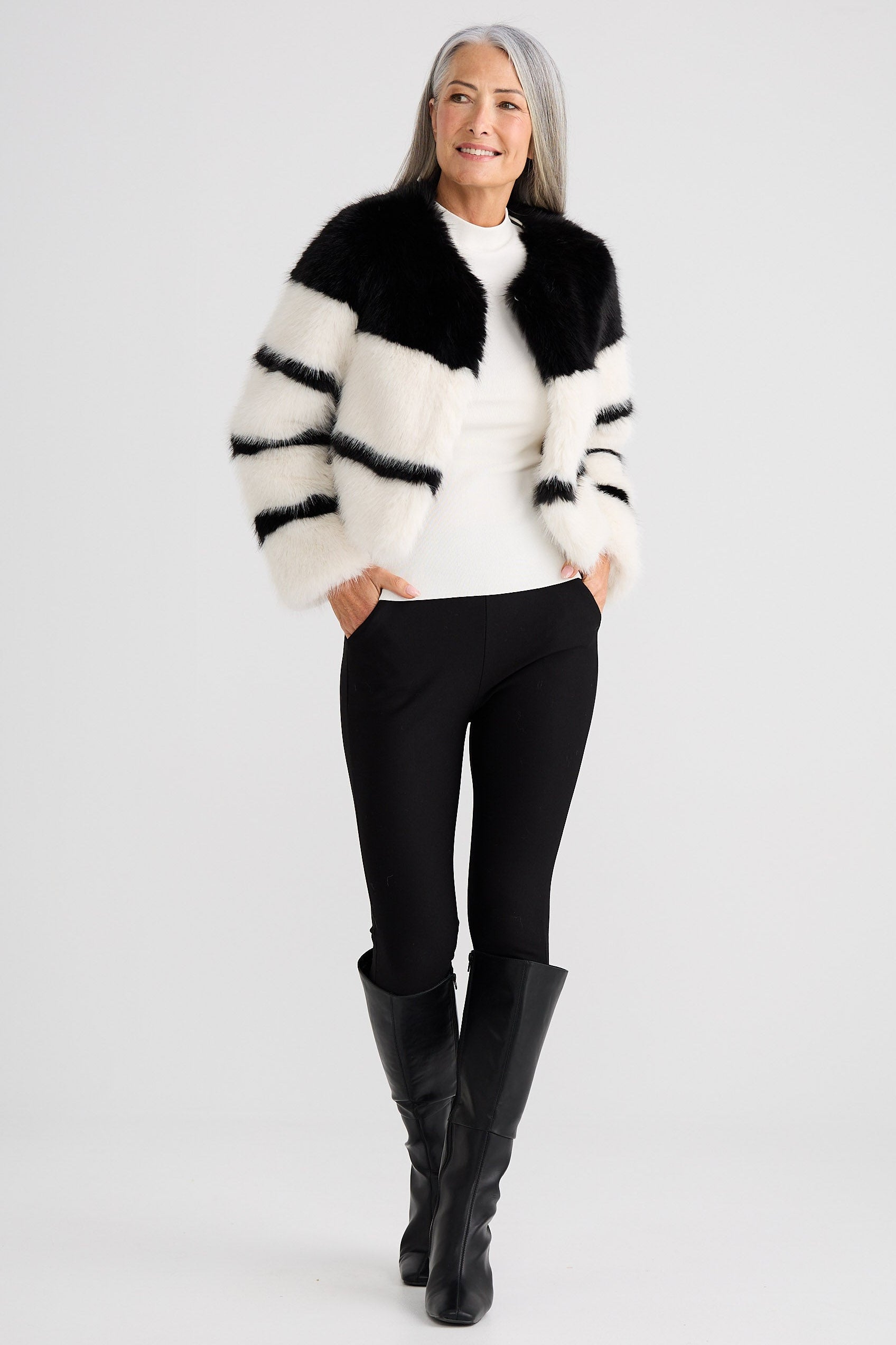 Woman wearing a black and white striped sweater with a fur collar on a white background