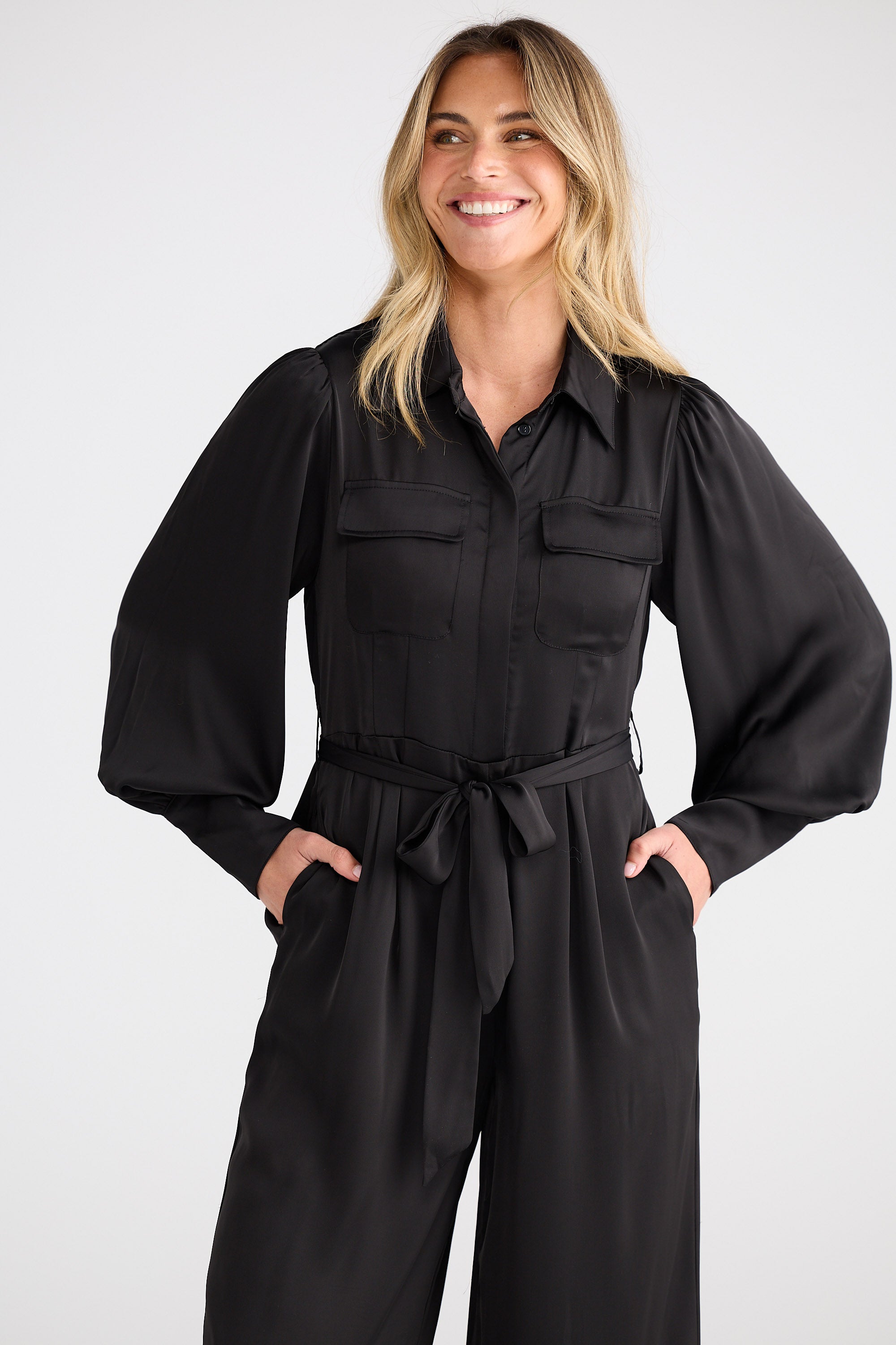 Woman wearing a black jumpsuit against a white background