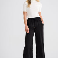Woman wearing a white top and black wide-leg pants on a white background