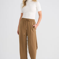 Woman wearing a white top and tan pants on a white background