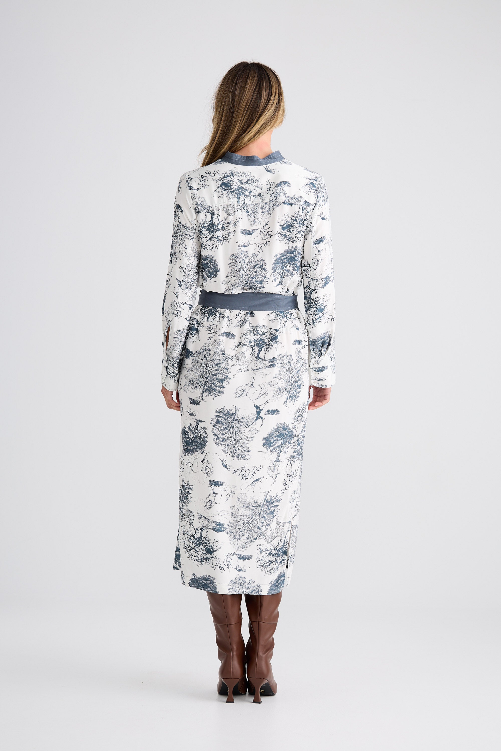 Woman wearing a long floral dress with a belt on a white background