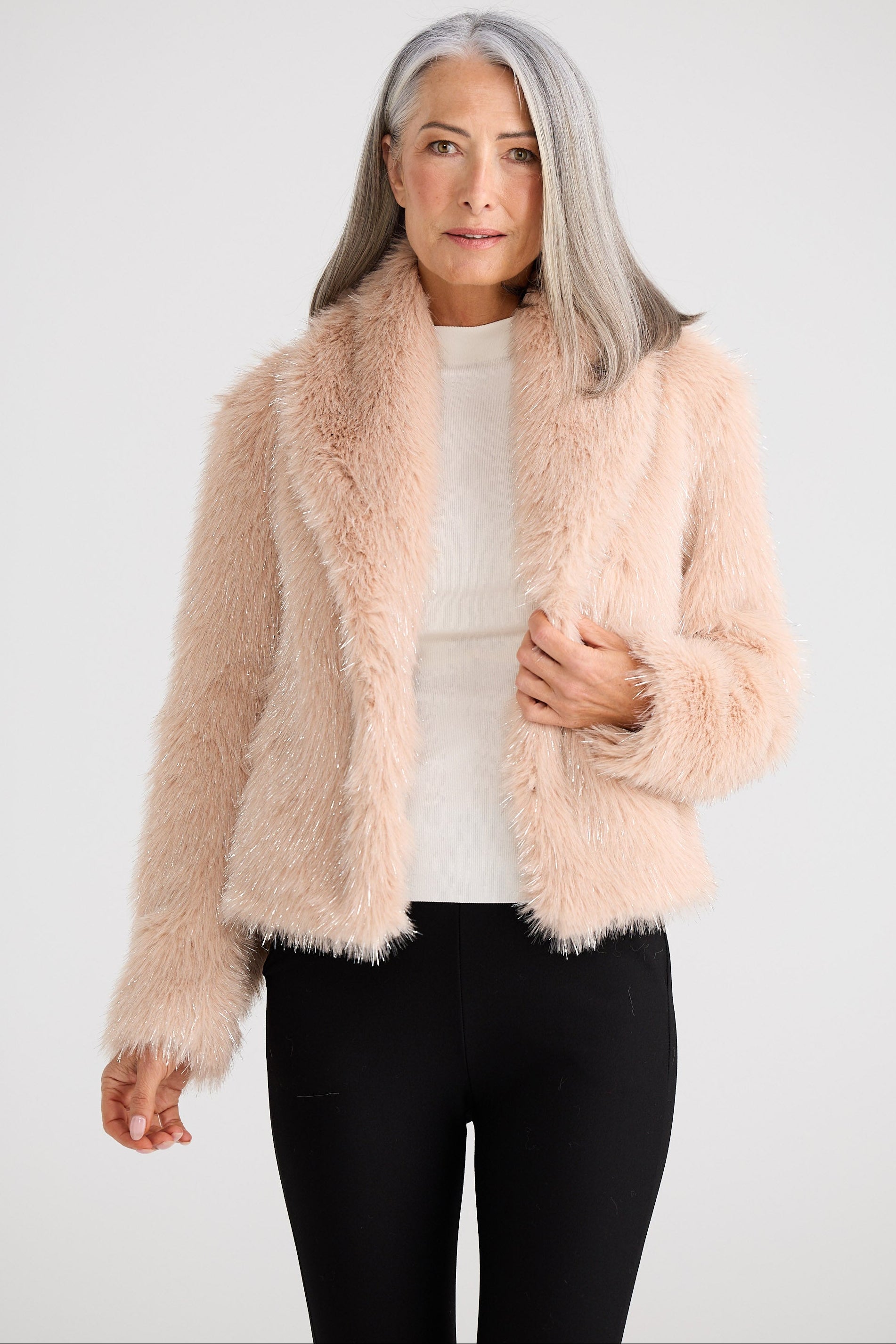 Woman wearing a light pink fluffy jacket against a white background