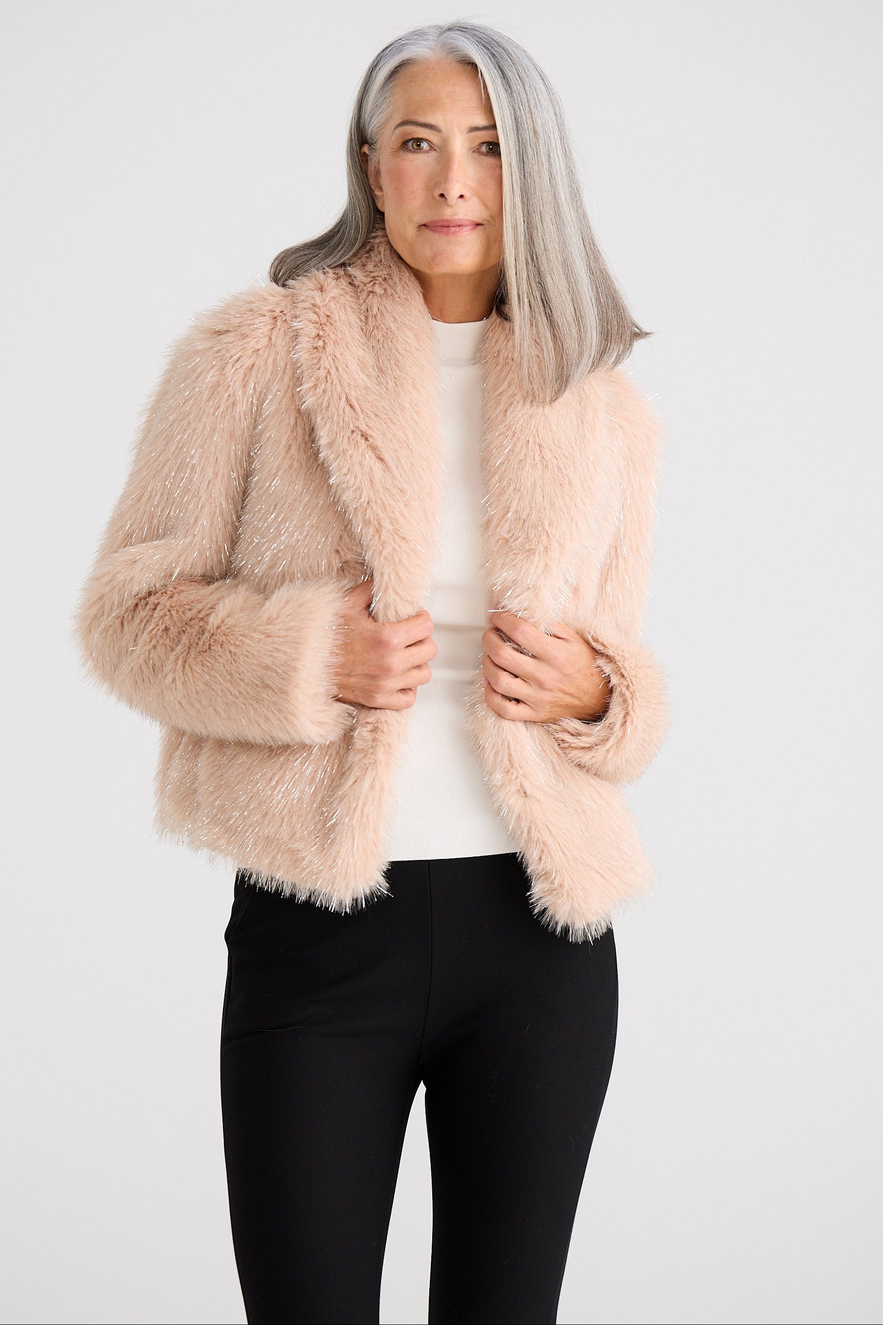 Woman wearing a fluffy pink jacket against a white background