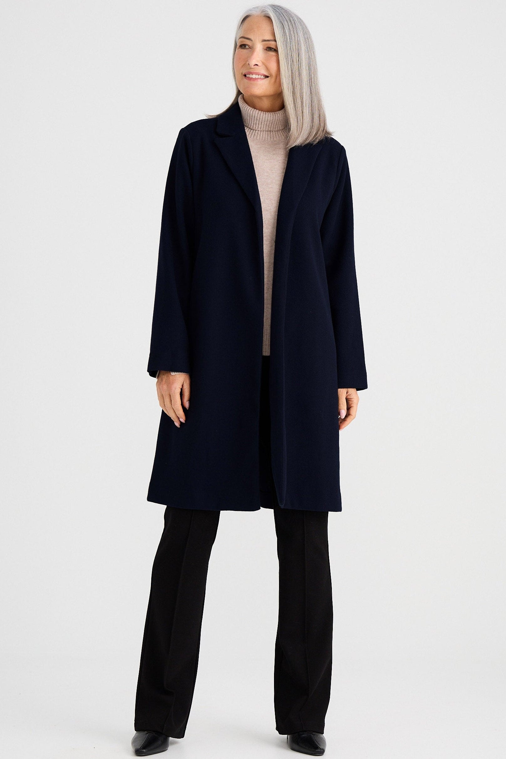 Person wearing a navy coat and black pants on a white background