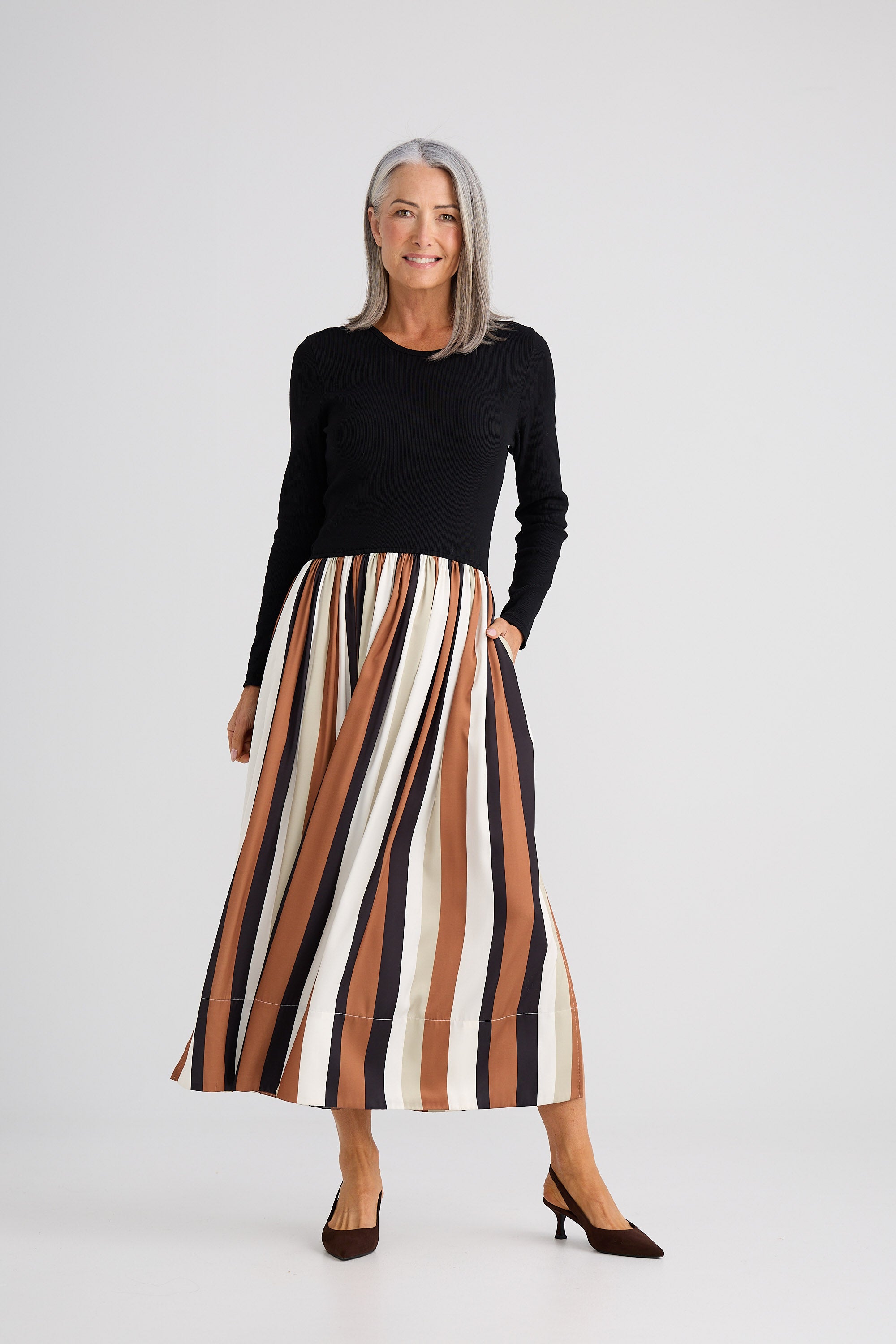 Woman wearing a black top and striped skirt on a white background