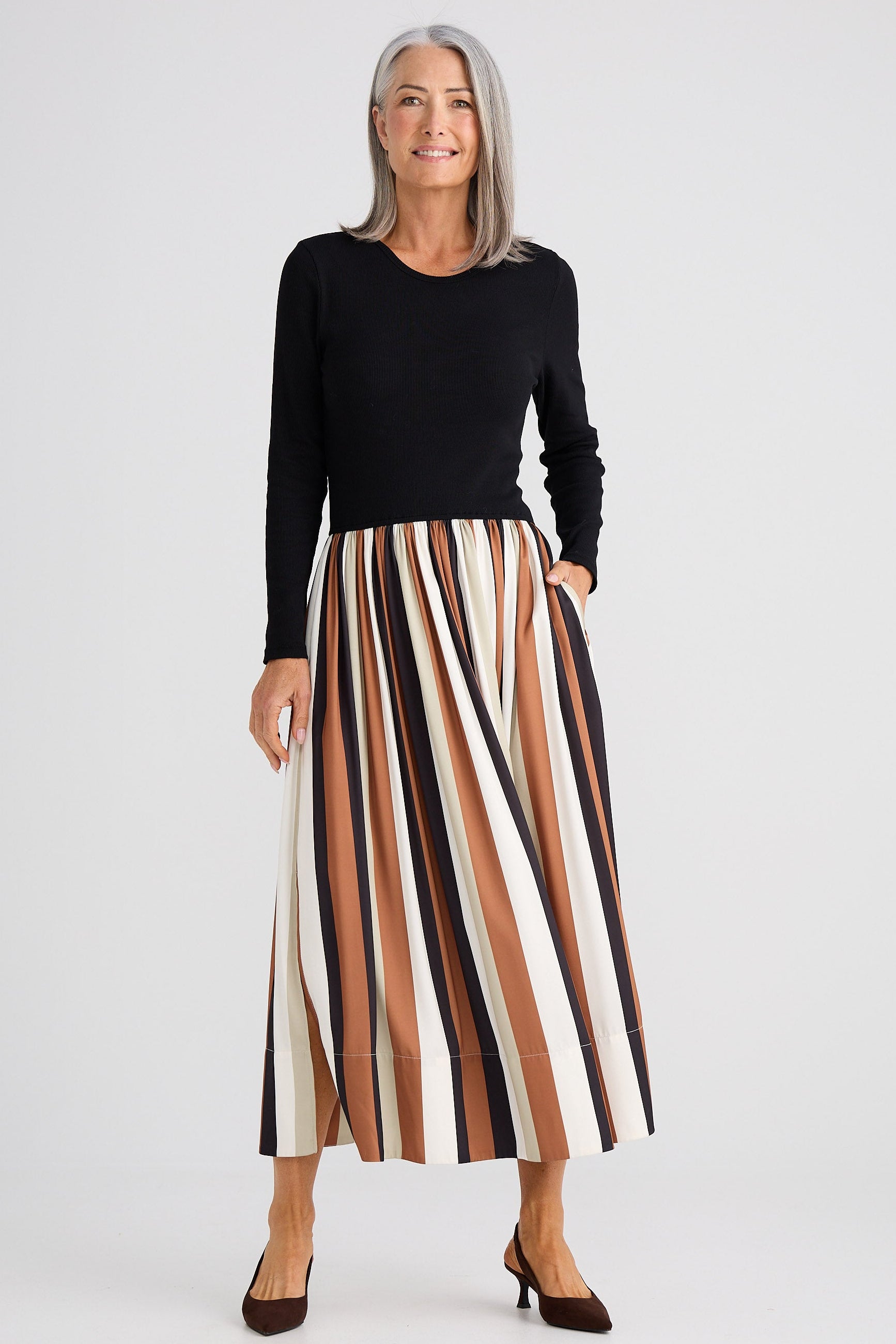 Woman wearing a black top and striped skirt on a white background