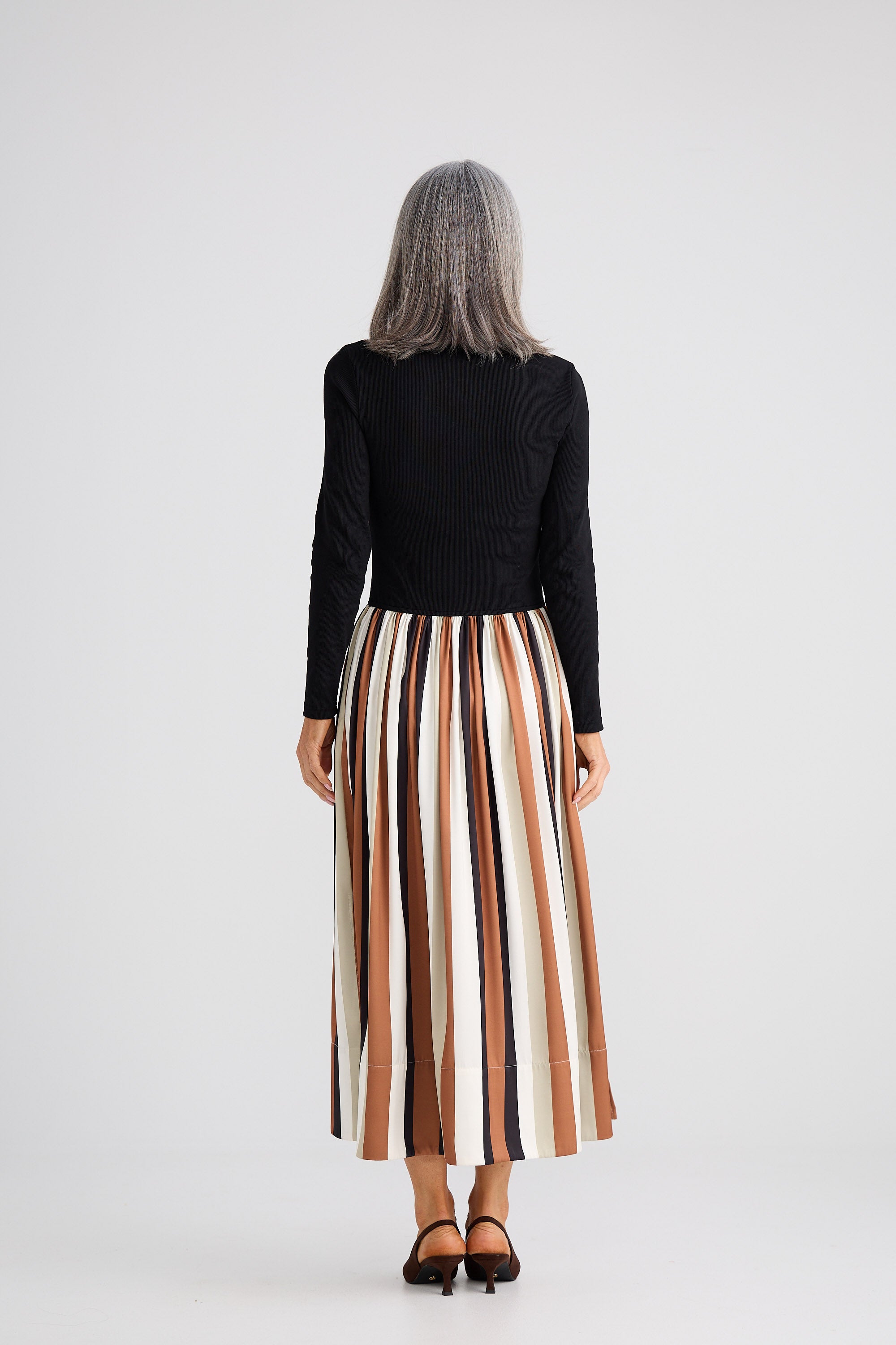 Person wearing a black top and striped skirt on a white background