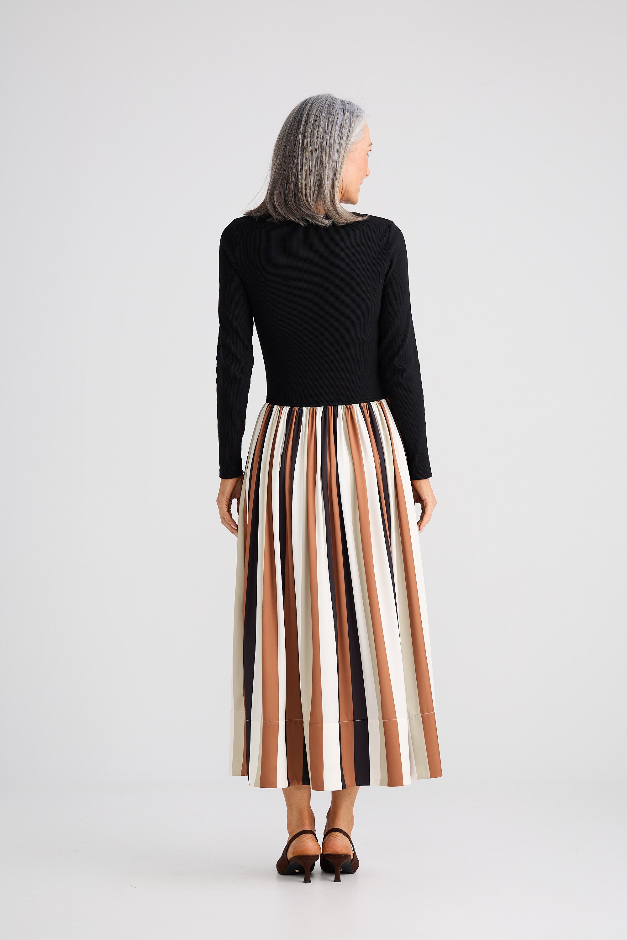 Person wearing a black top and striped skirt on a white background