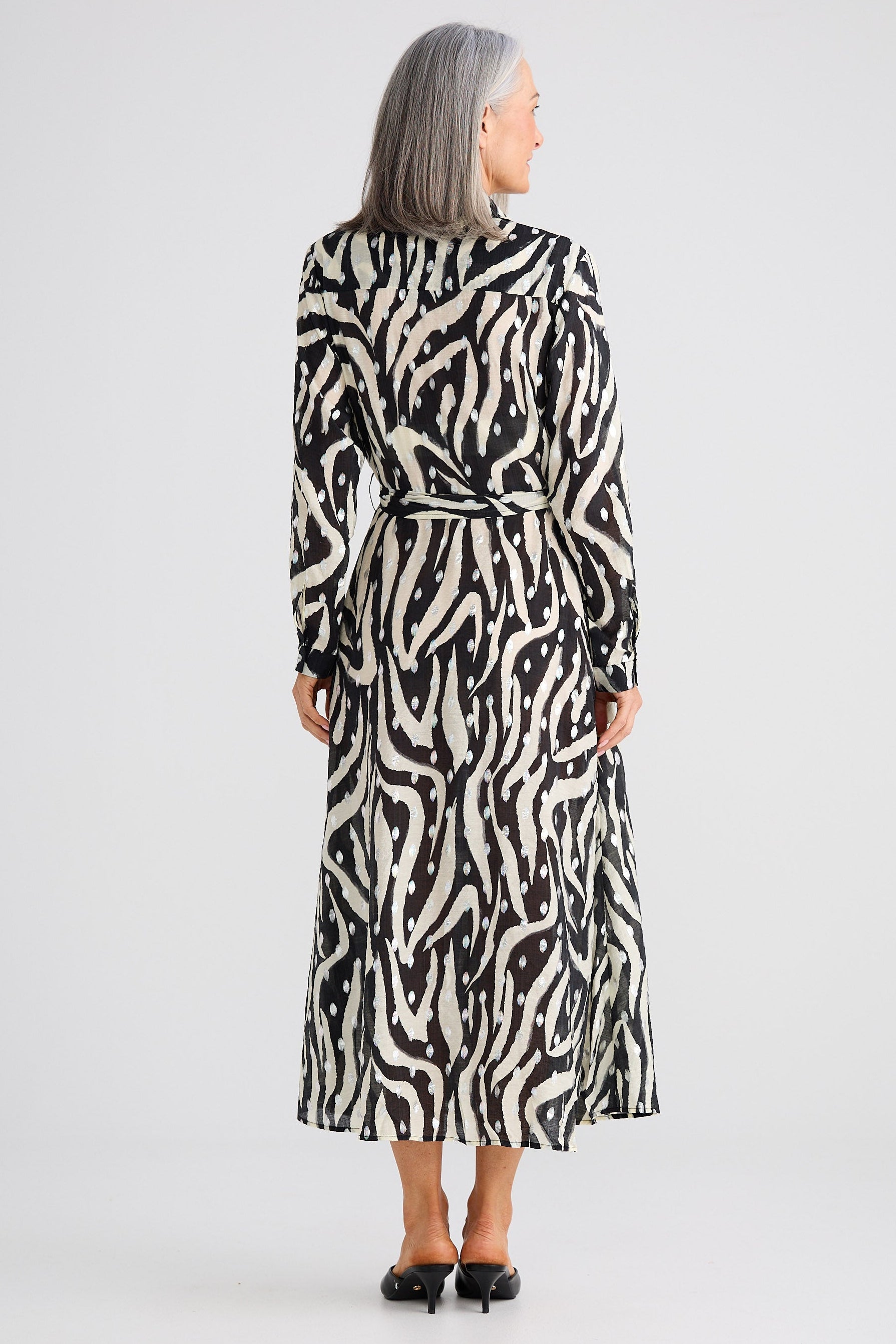 Woman wearing a black and white patterned dress on a white background