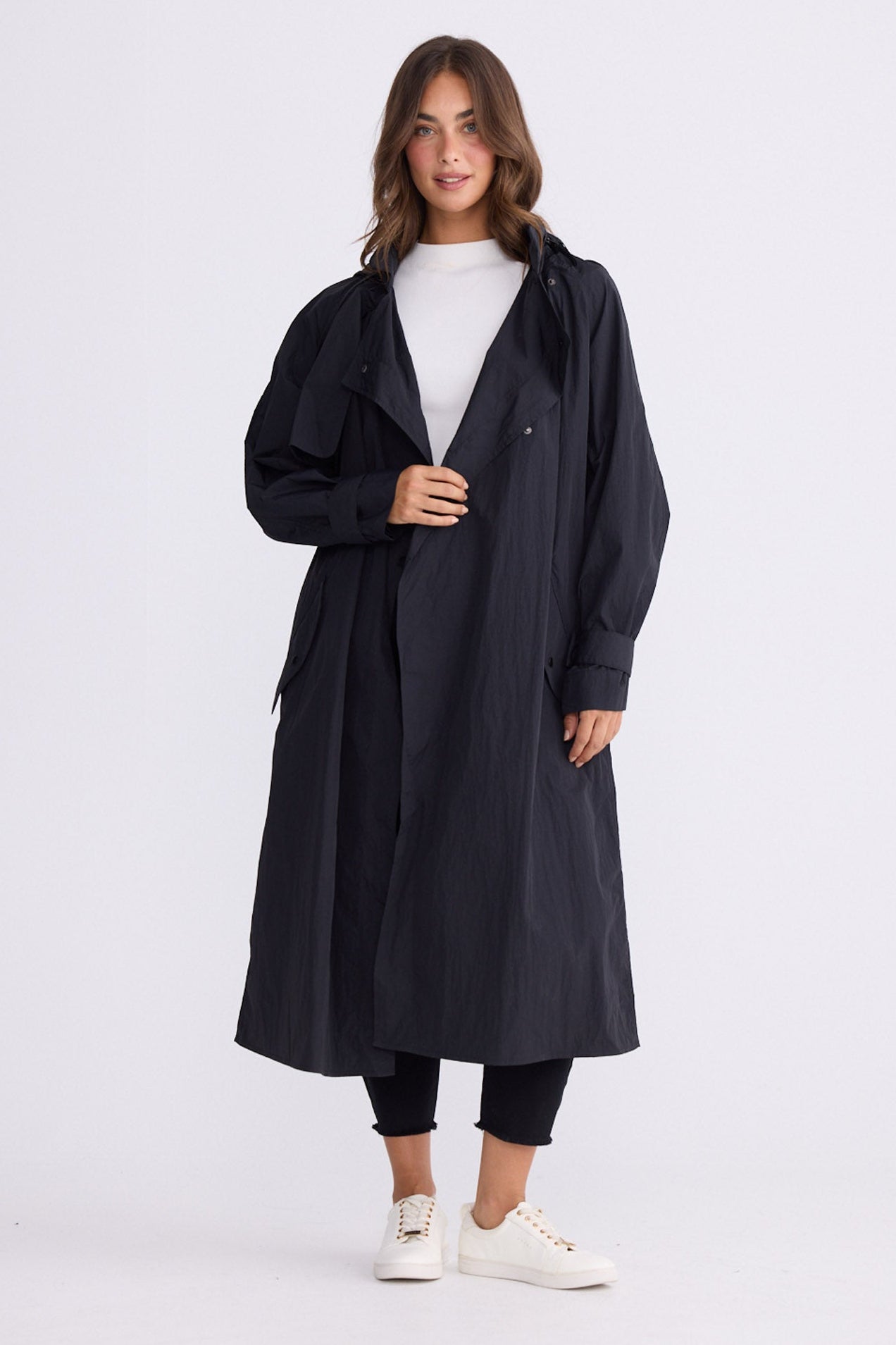 Model wearing Cressida Raincoat black coat, front pockets, alternate studio view on white background