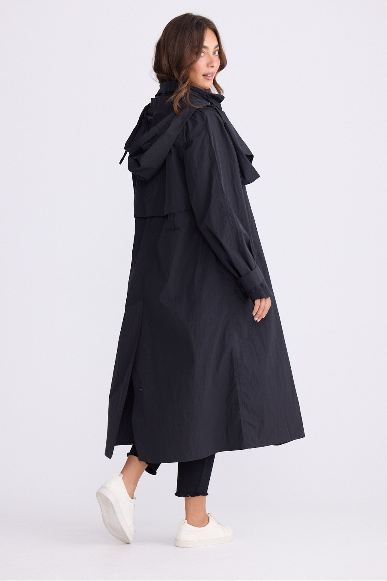 Model wearing Cressida Raincoat black coat, front pockets, front view on white background