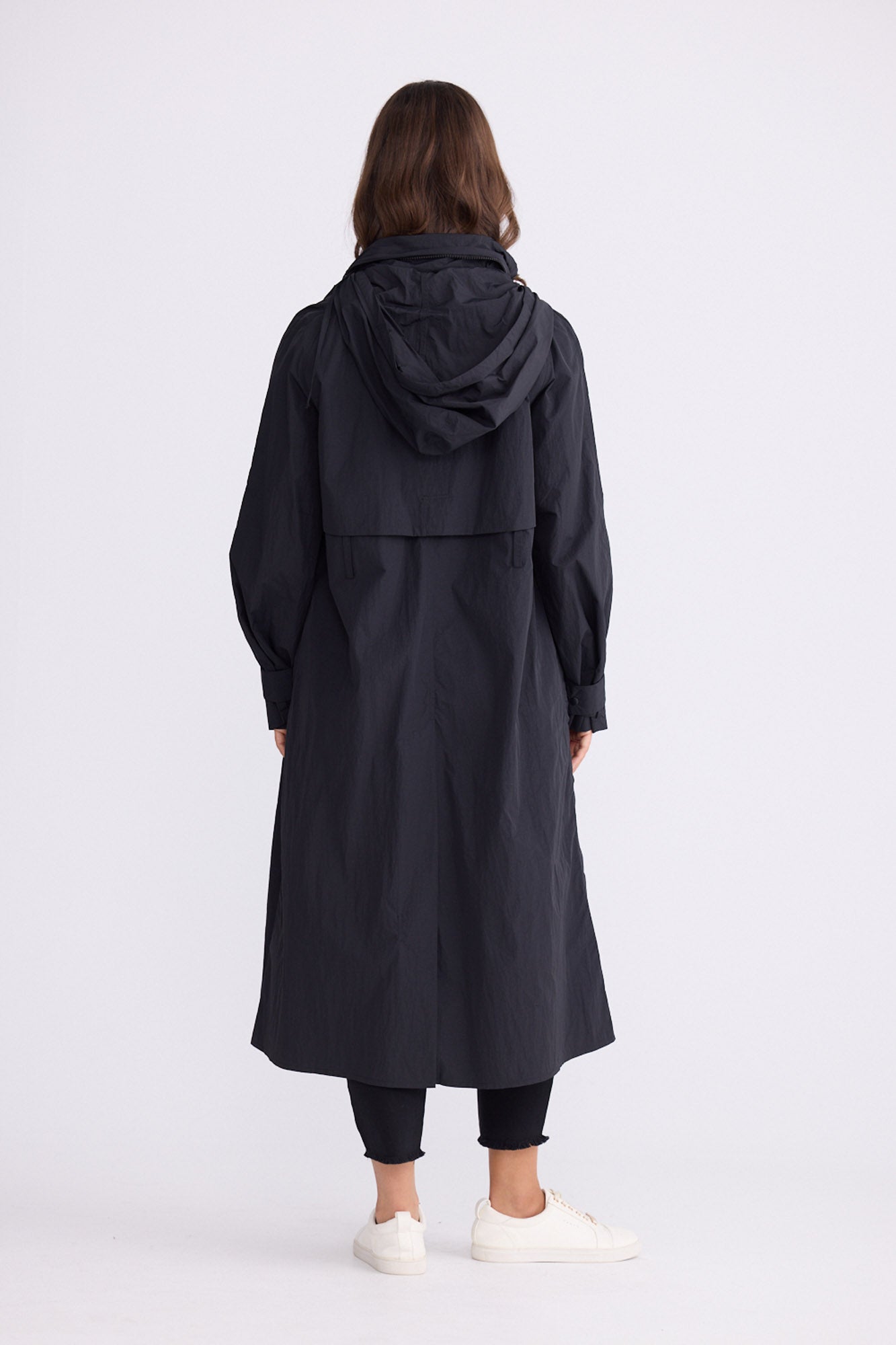 Model wearing Cressida Raincoat black coat, front pockets, alternate studio view on white background