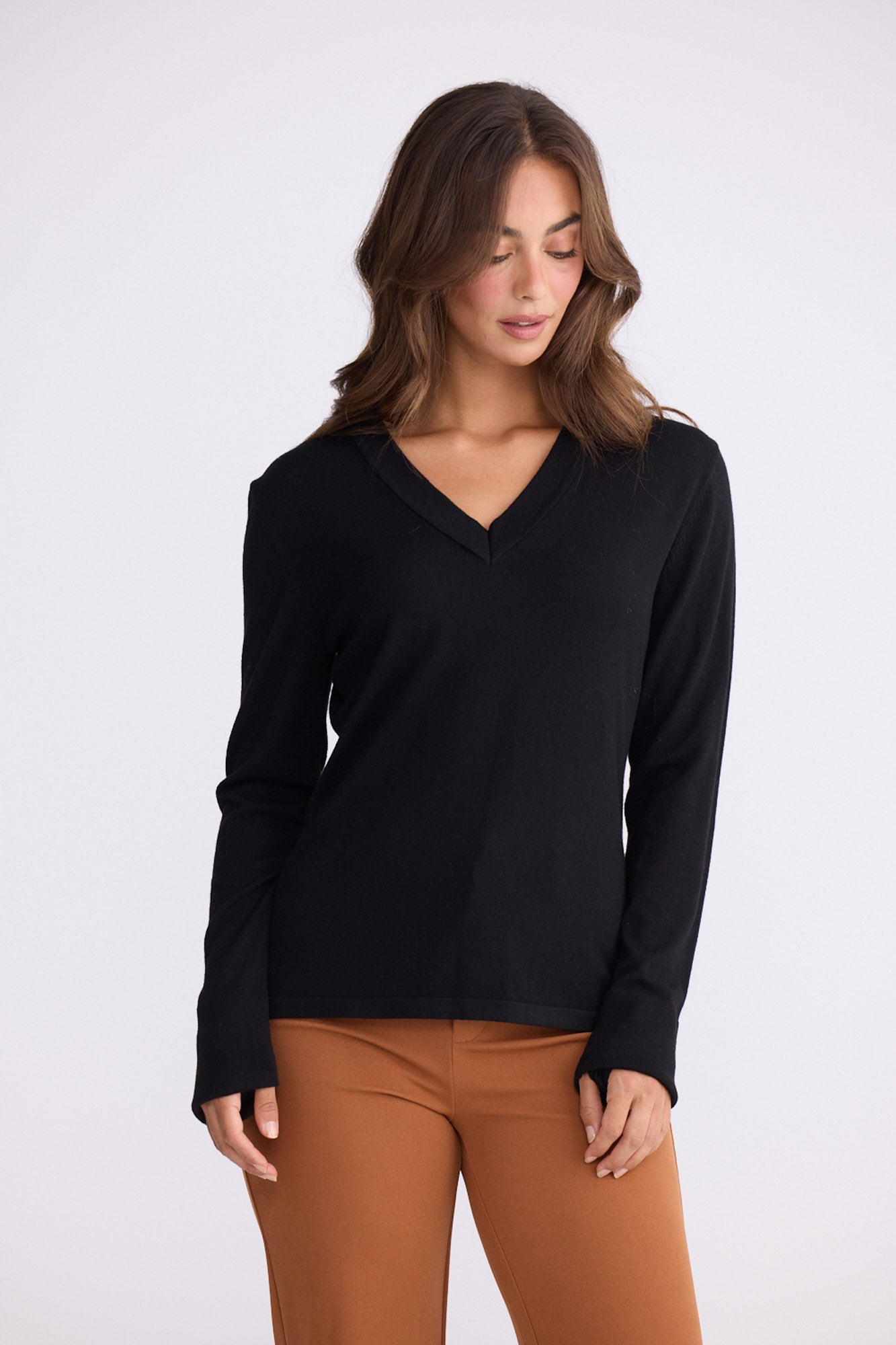 Model wearing Cassian LS Knit Top - Black, studio view on white background