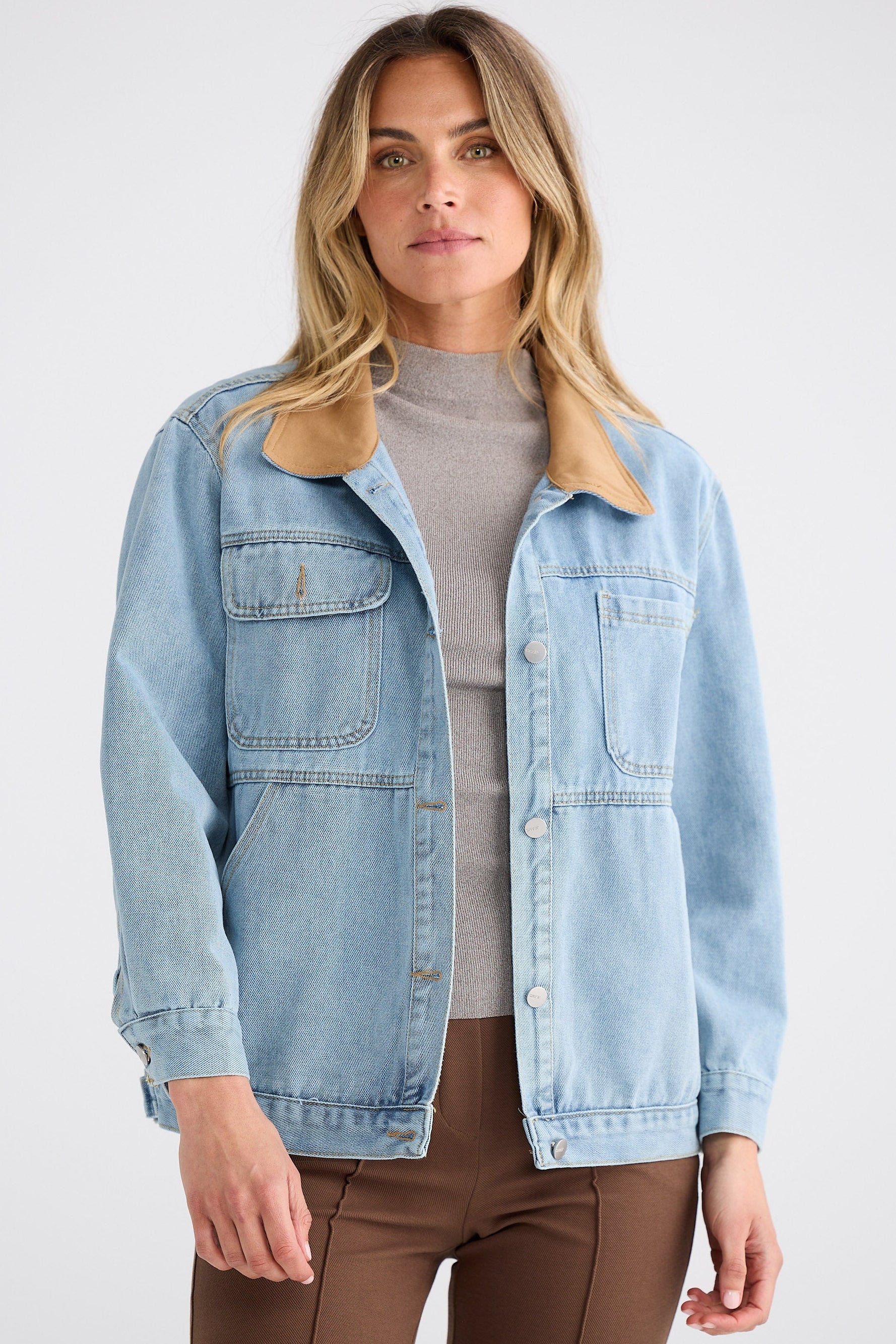 Woman wearing a light blue denim jacket on a white background