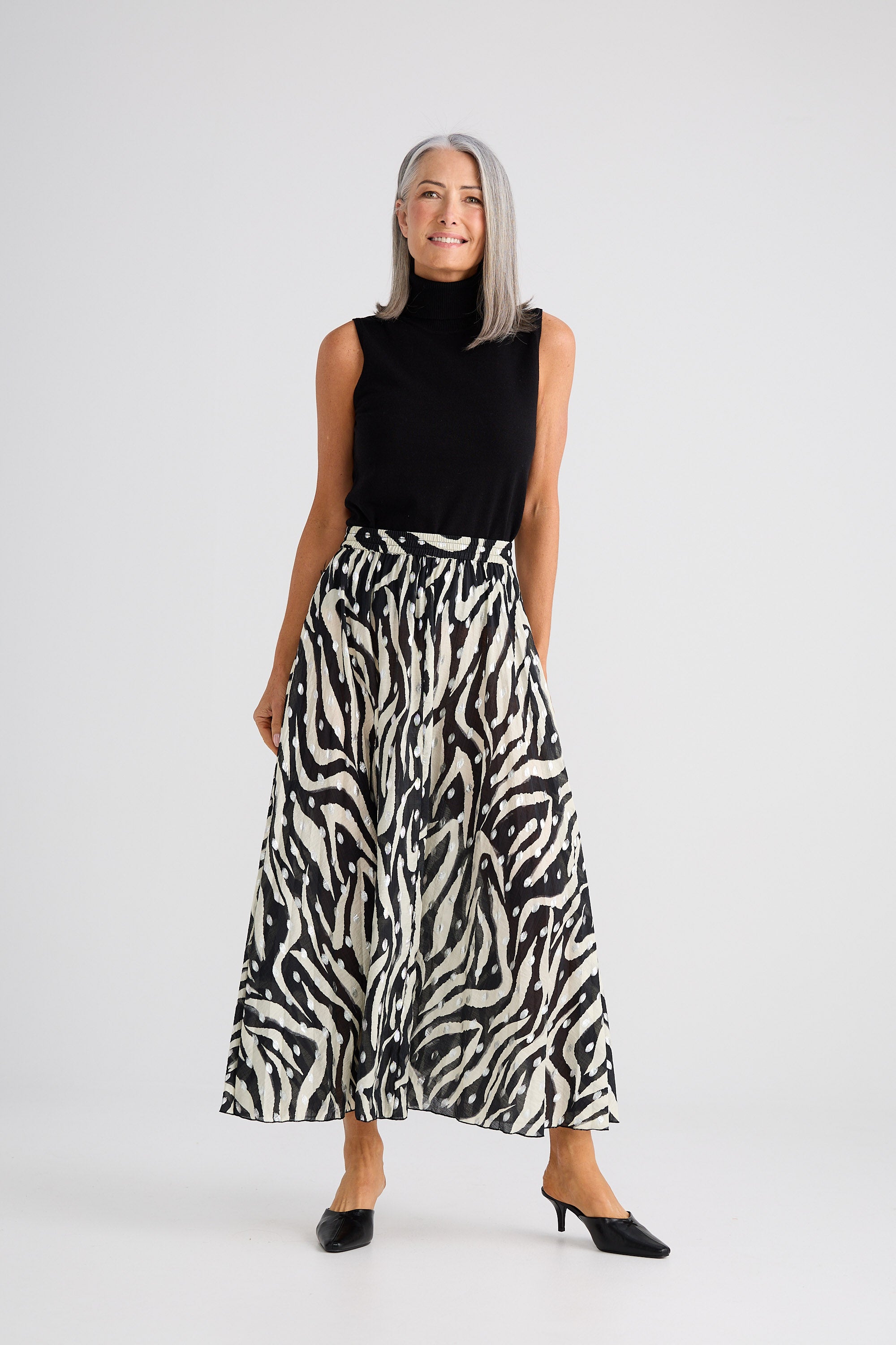 Woman wearing a black sleeveless top and zebra print skirt on a white background