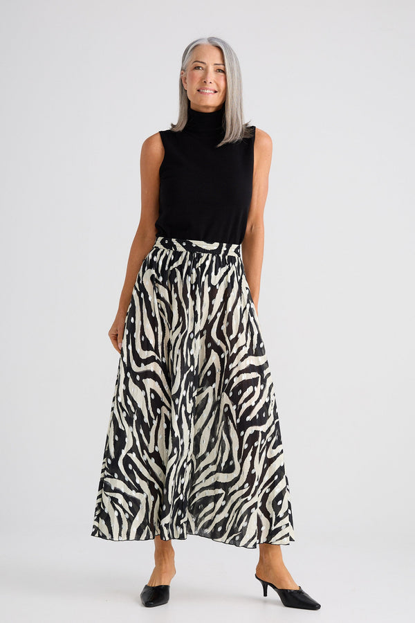 Woman wearing a black sleeveless top and zebra print skirt on a white background