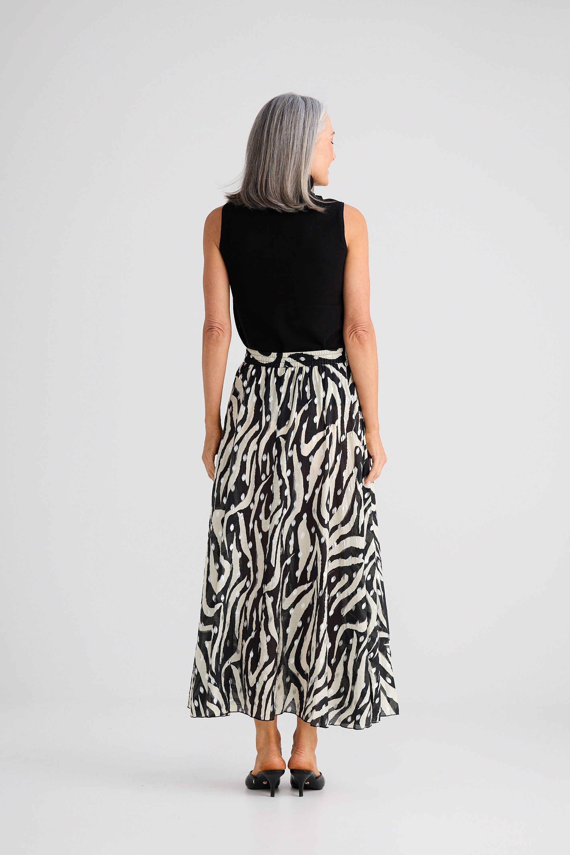 Person wearing a black sleeveless top and zebra print skirt on a white background
