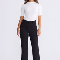 Model wearing Tressa black flared pants with high-rise waist, front view on white background