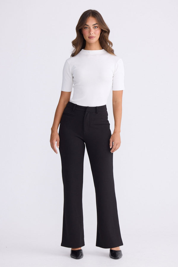 Model wearing Tressa black flared pants with high-rise waist, front view on white background