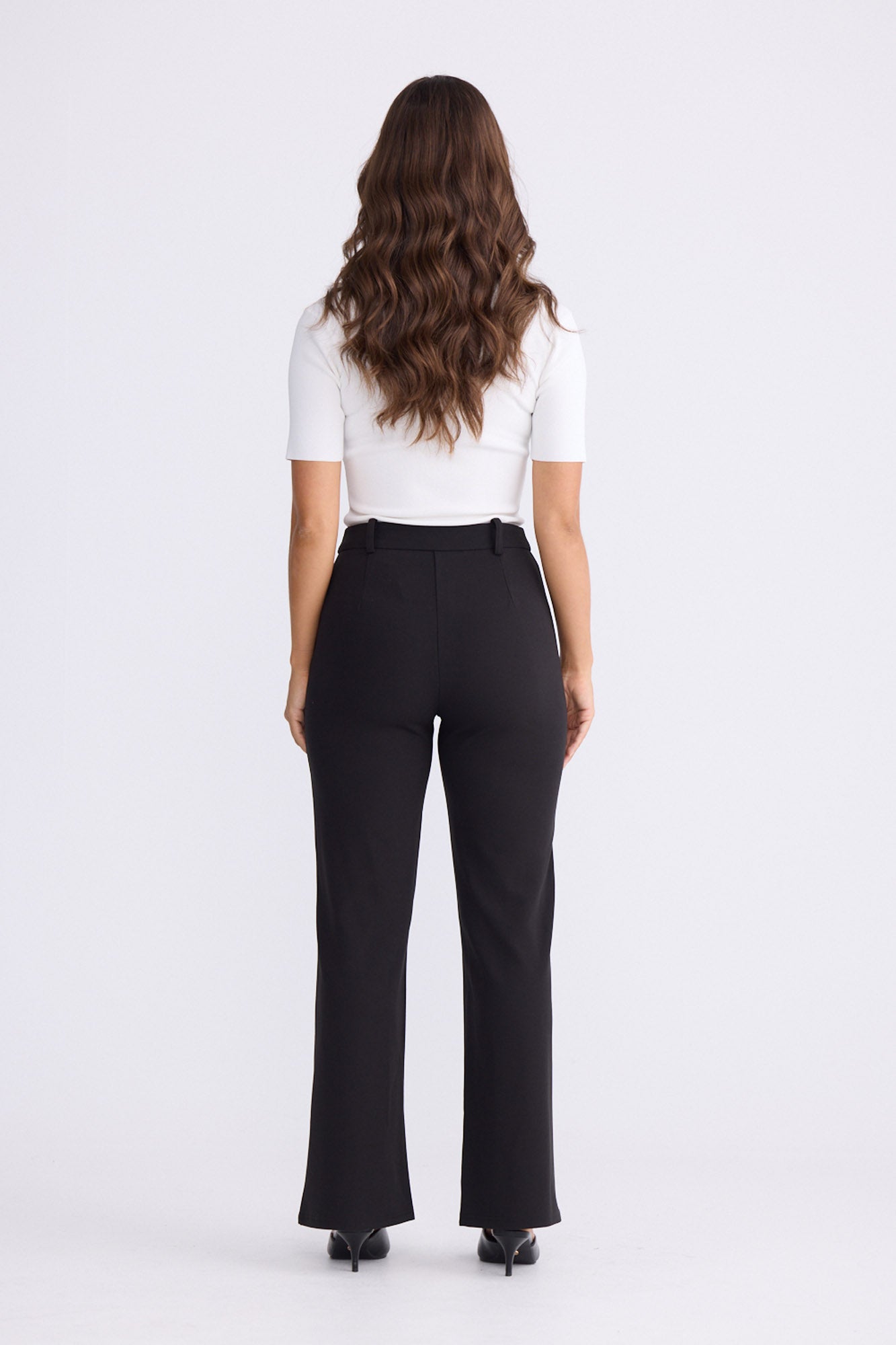 Model wearing Tressa black flared pants with high-rise waist, alternate view on white background