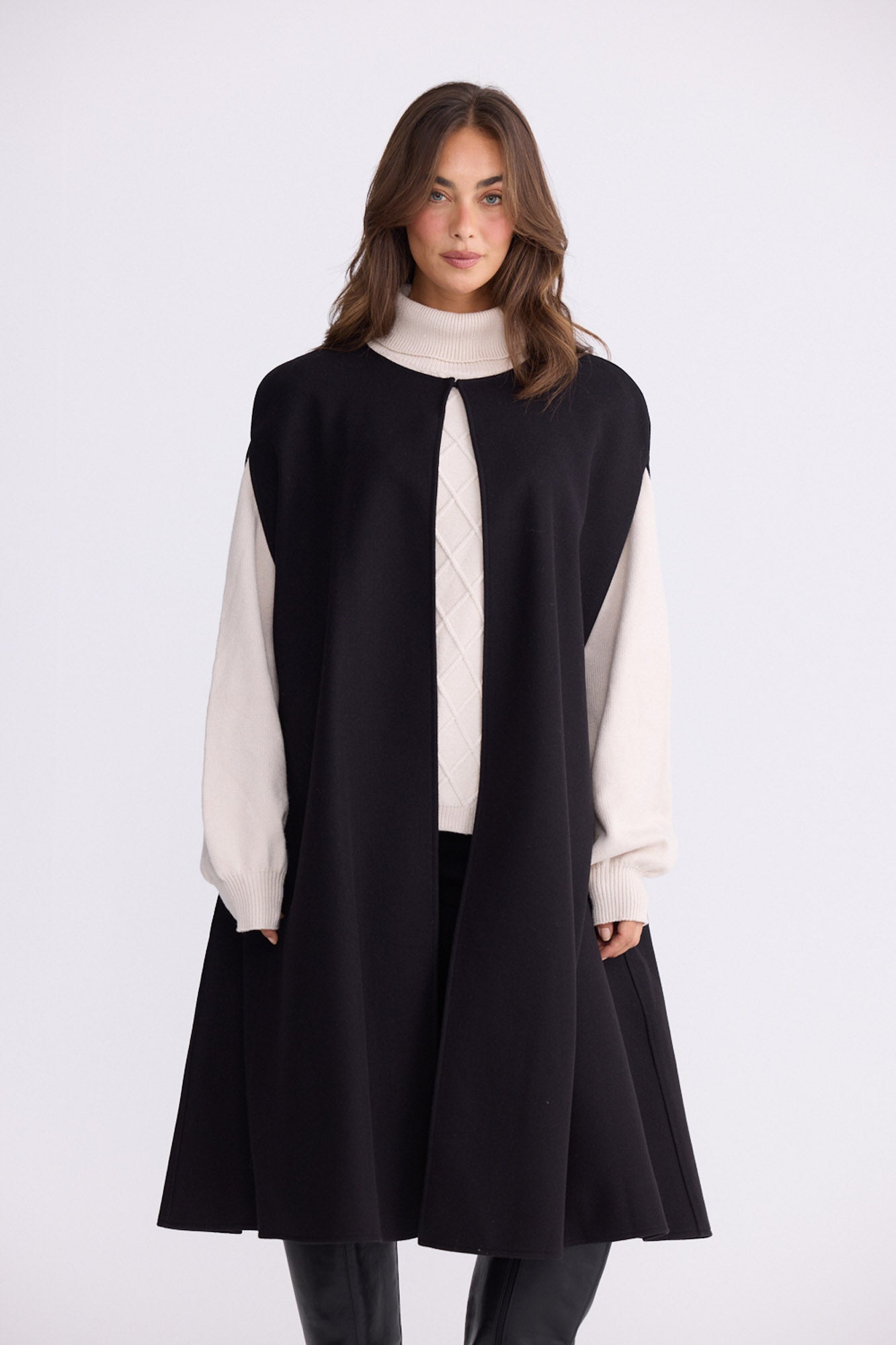 Model wearing Trini black sleeveless cape with long fluid silhouette, alternate view on white background