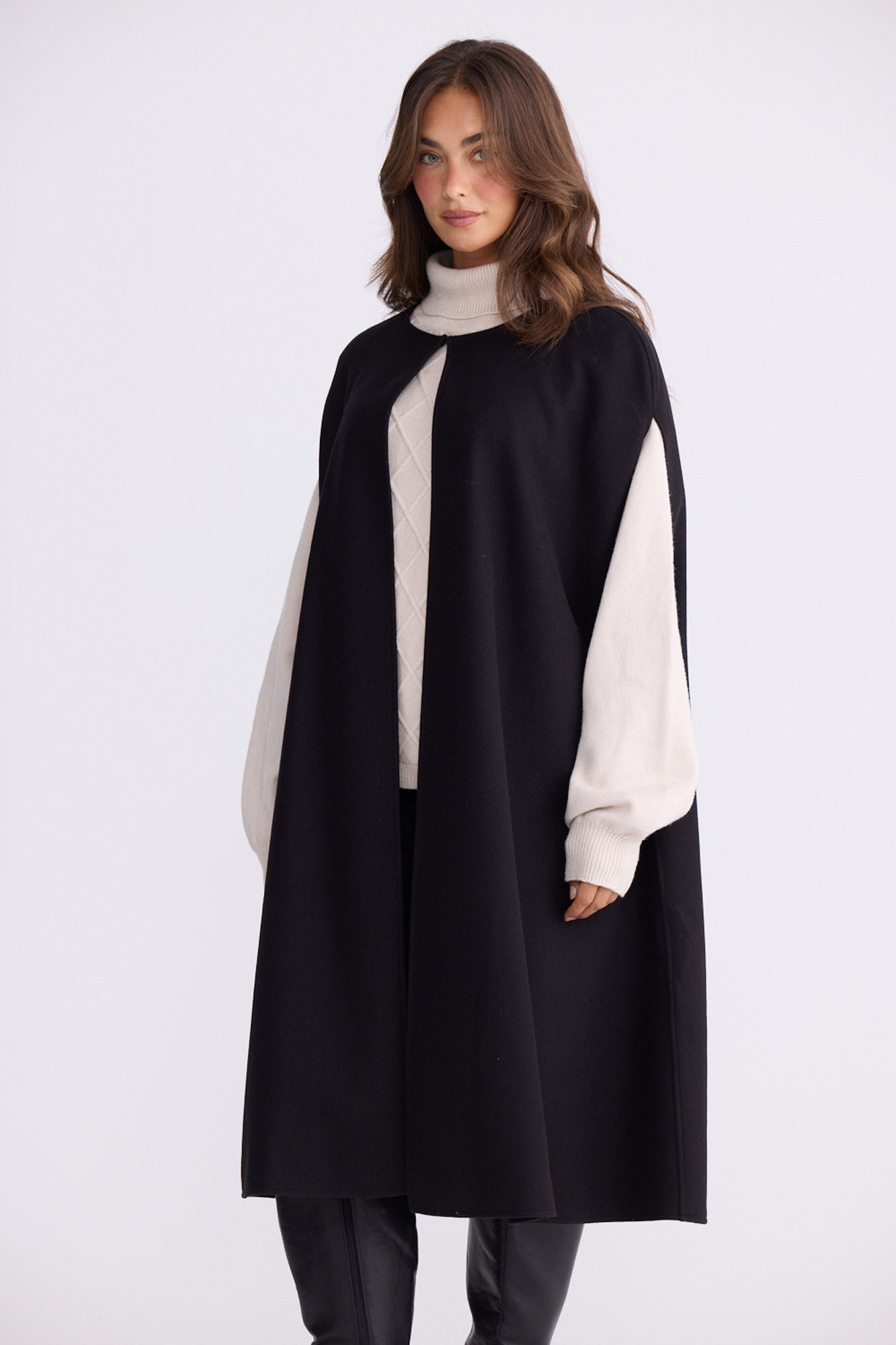 Model wearing Trini black sleeveless cape with long fluid silhouette, alternate view on white background