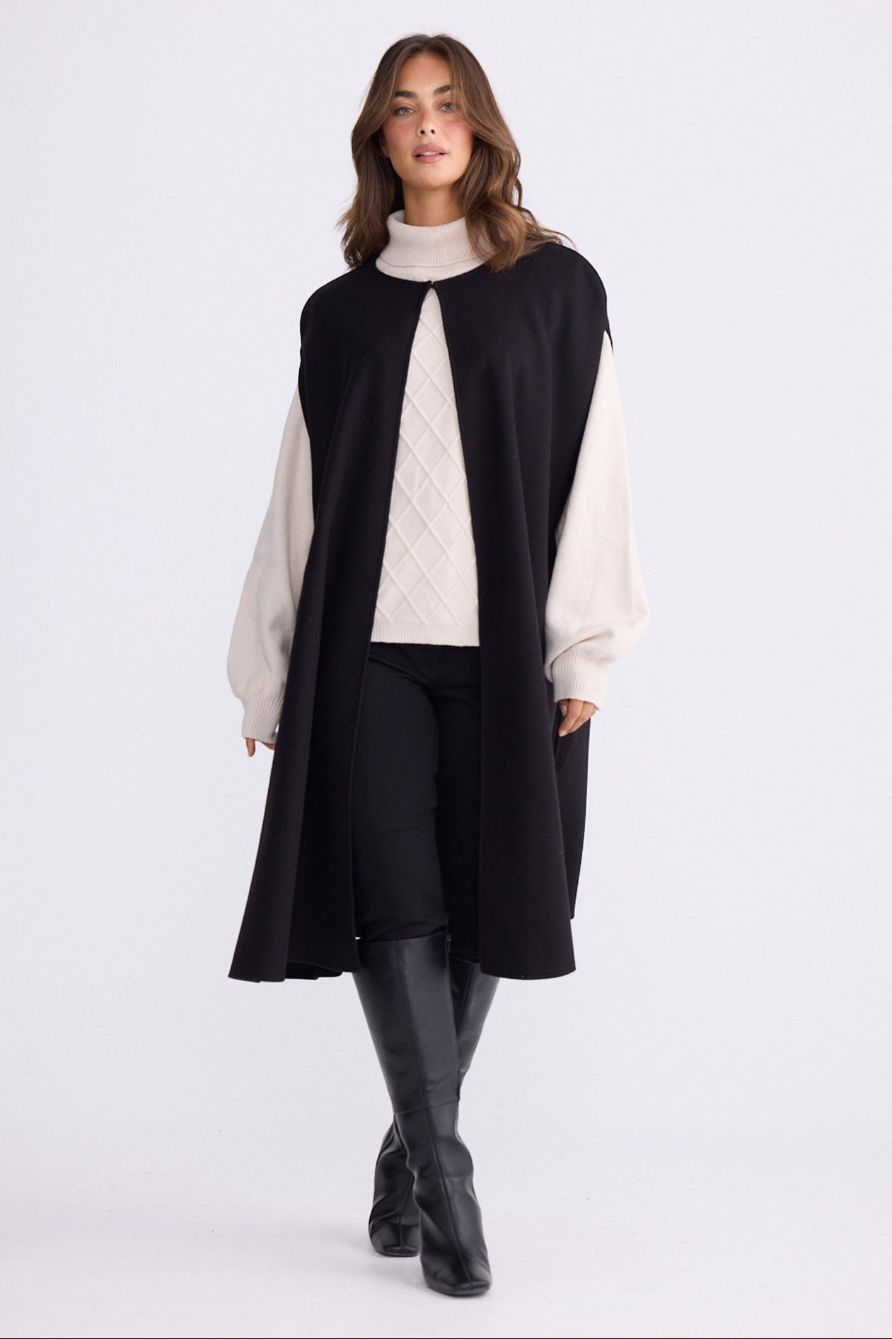 Model wearing Trini black sleeveless cape with long fluid silhouette, alternate view on white background