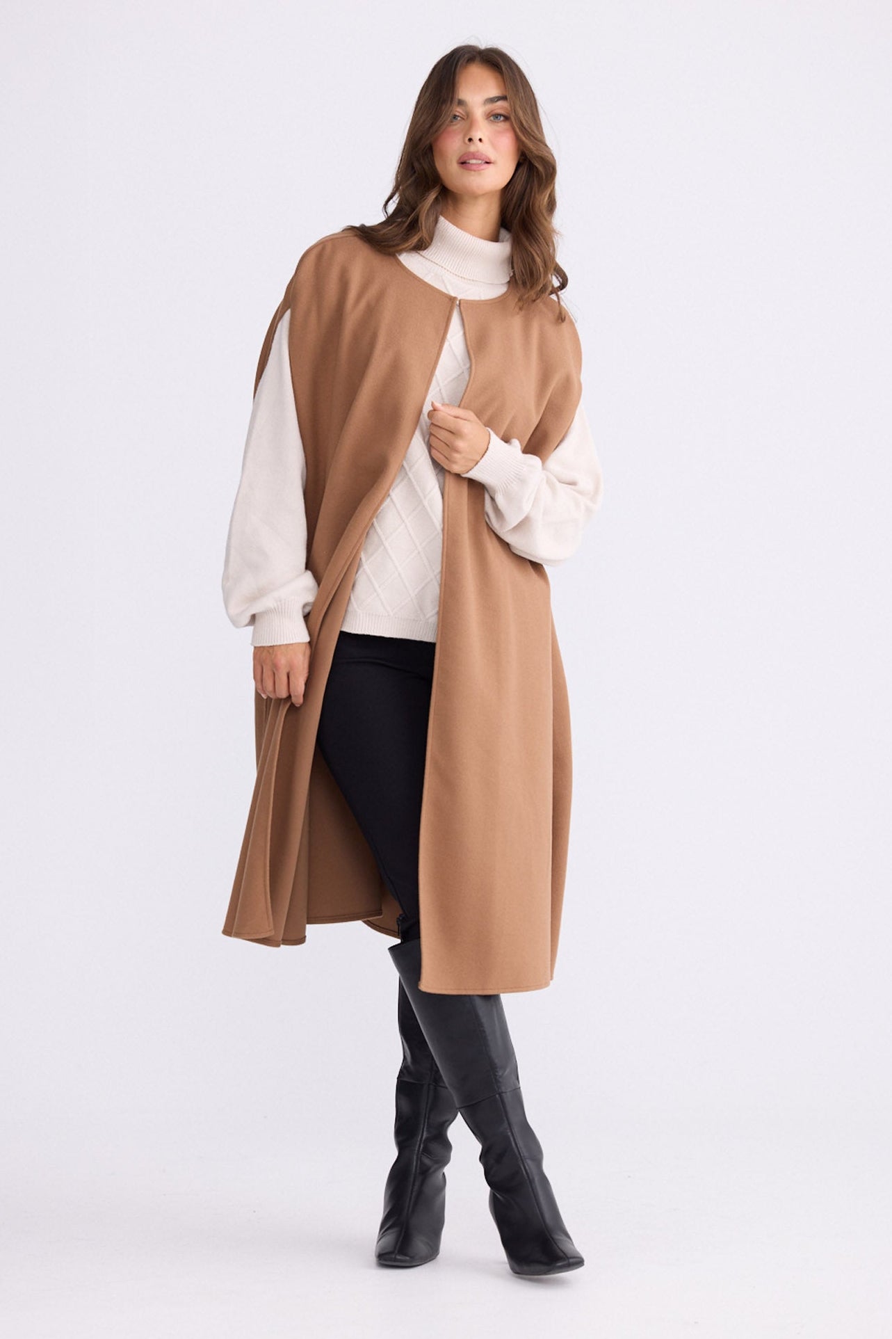 Model wearing Trini camel sleeveless cape with long fluid silhouette, front view on white background