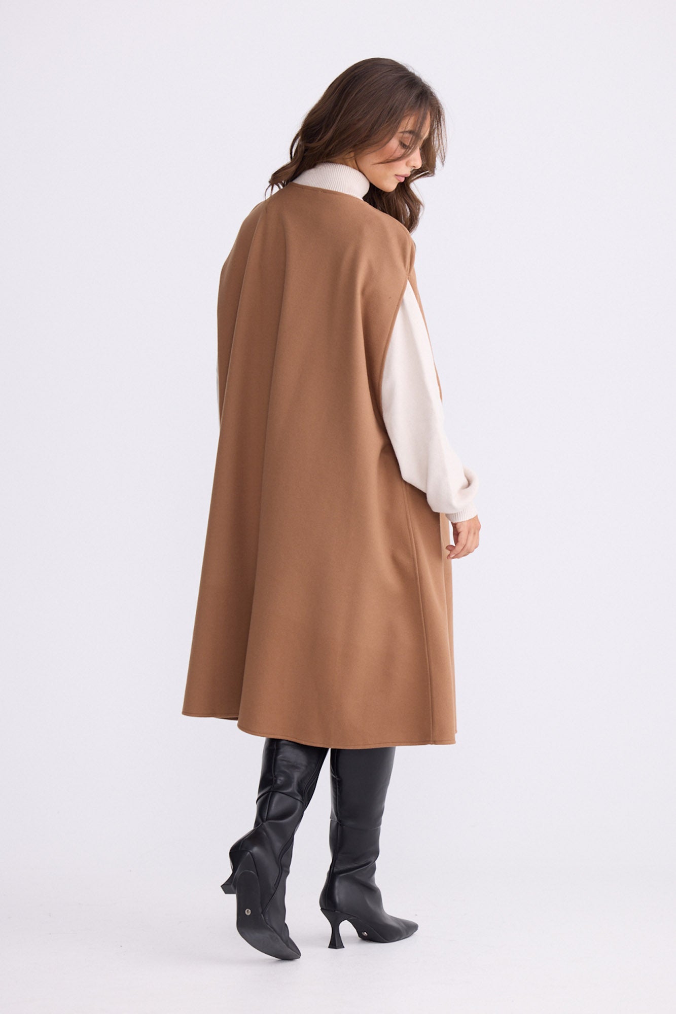 Model wearing Trini camel sleeveless cape with long fluid silhouette, alternate view on white background