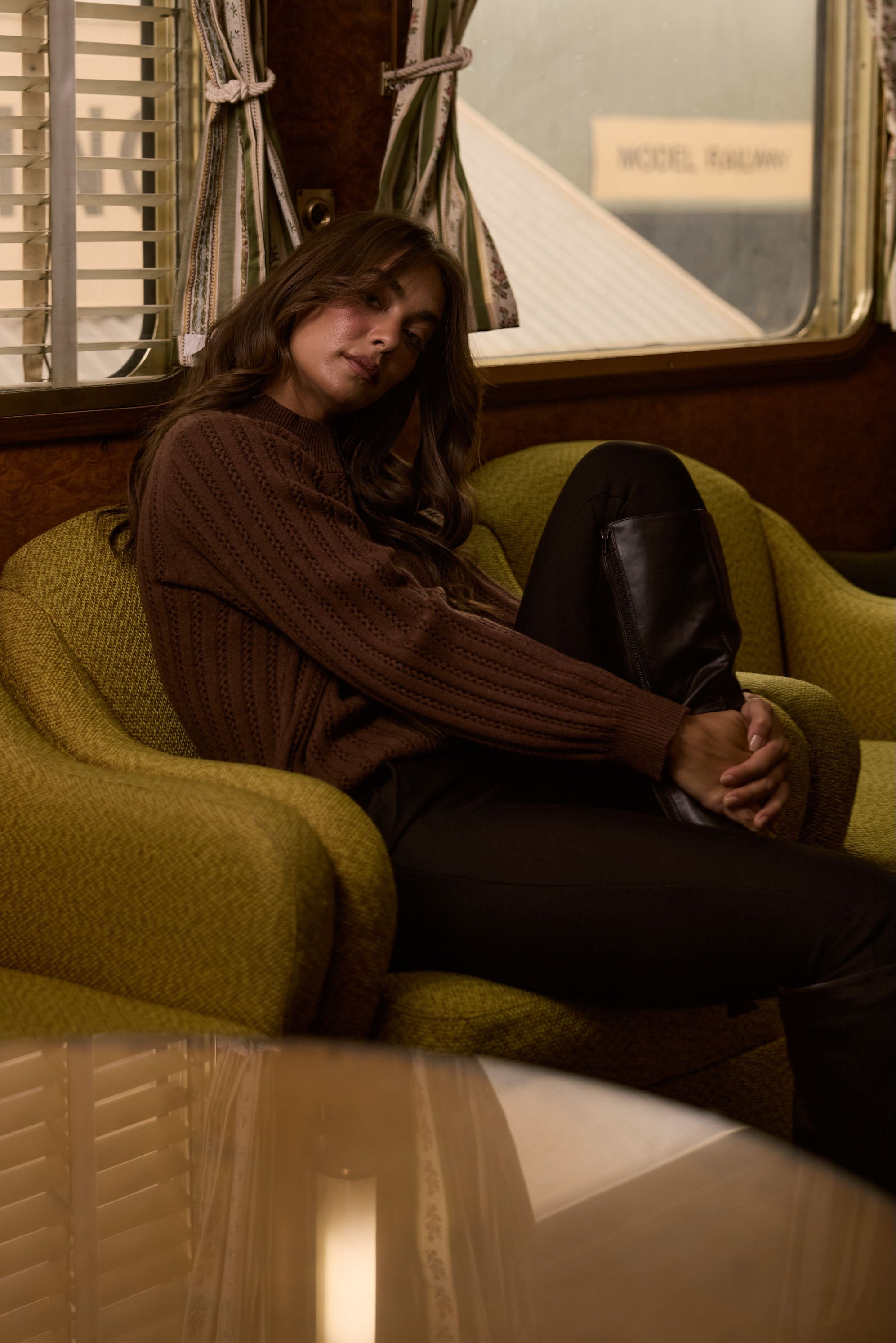 Model wearing Shea Knit in brown with crew neckline and long sleeves, side view on white background