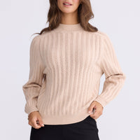 Model wearing Shea Knit in beige with textured knit, back view on white background