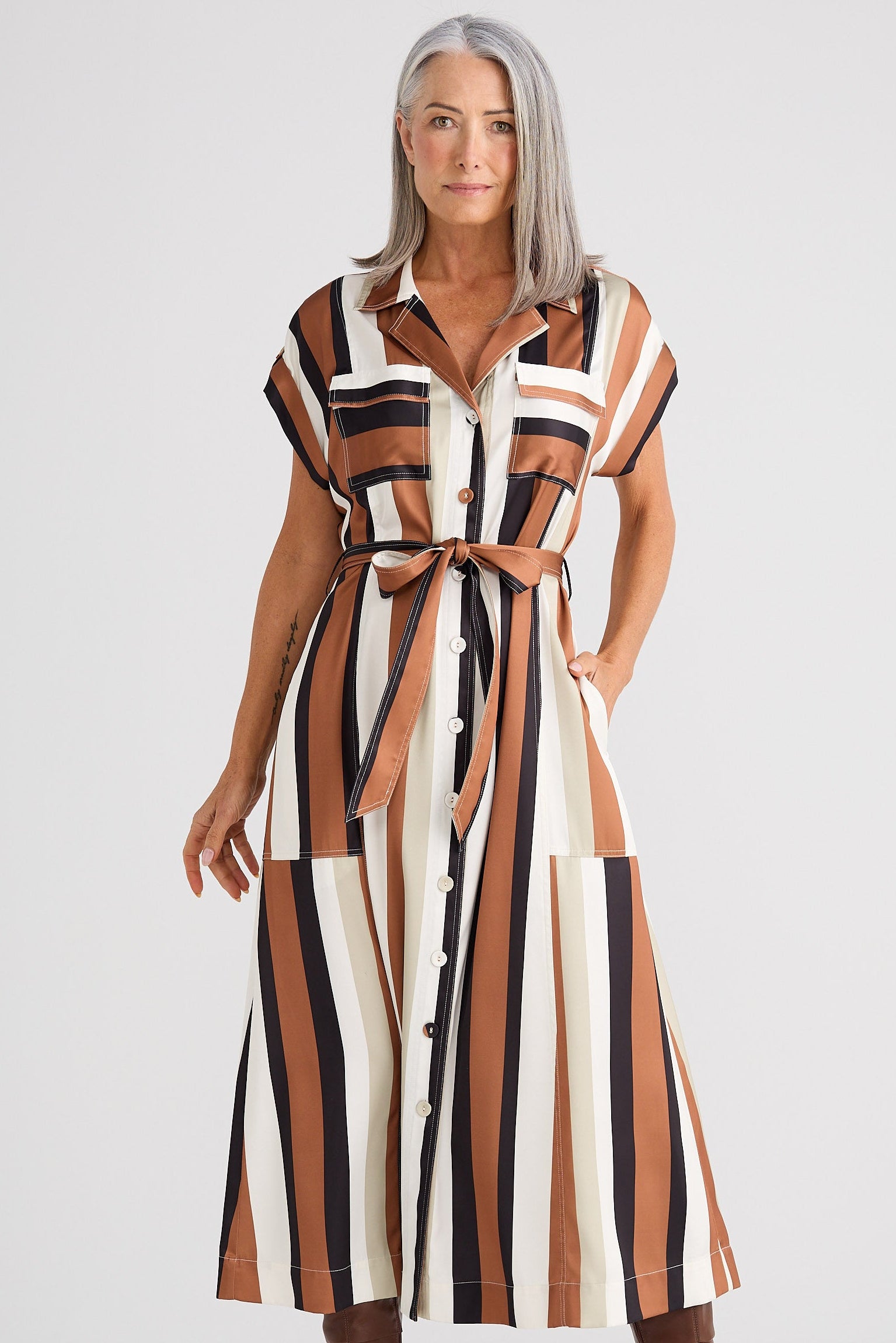 Woman wearing a striped dress with a belt on a white background