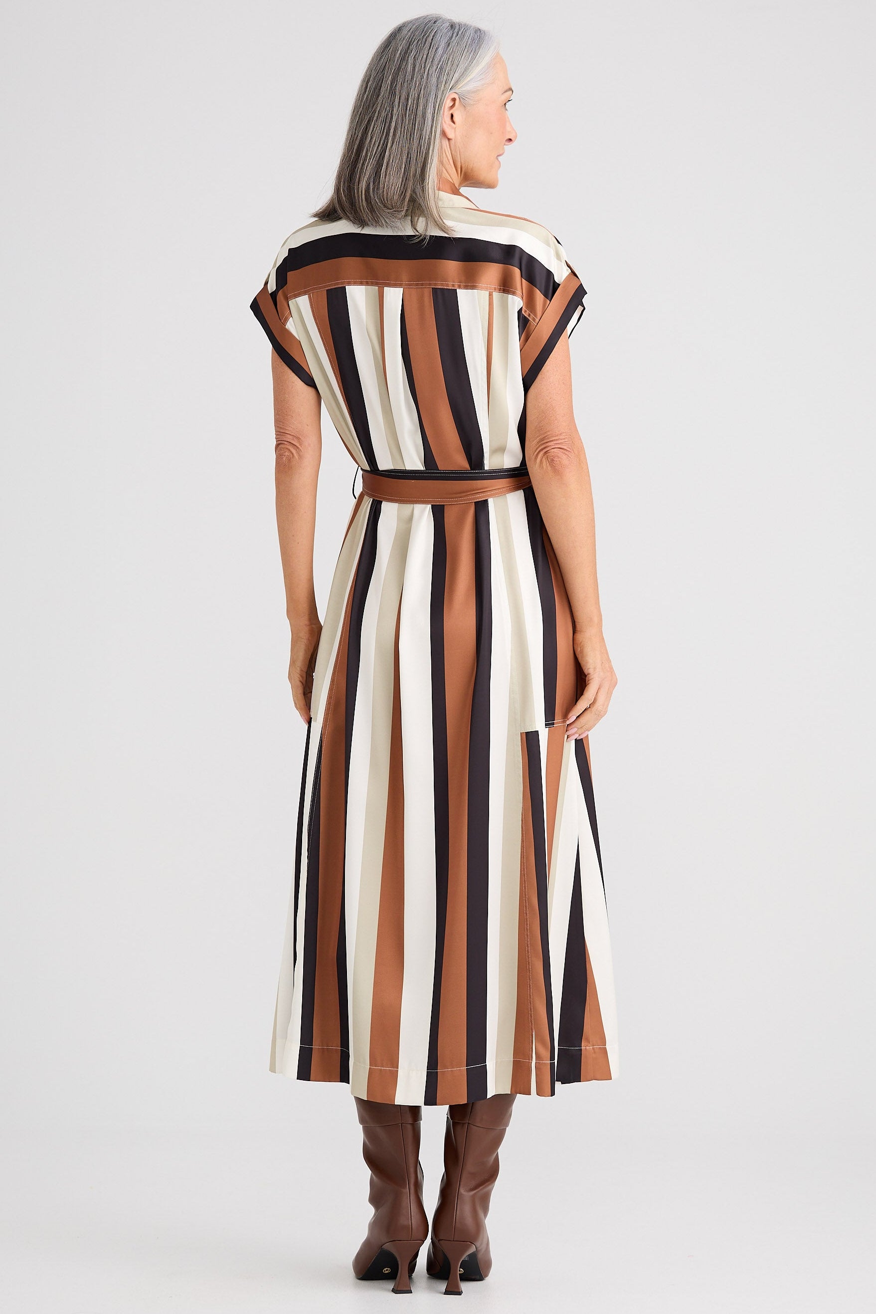 Woman wearing a striped dress with a belt on a white background