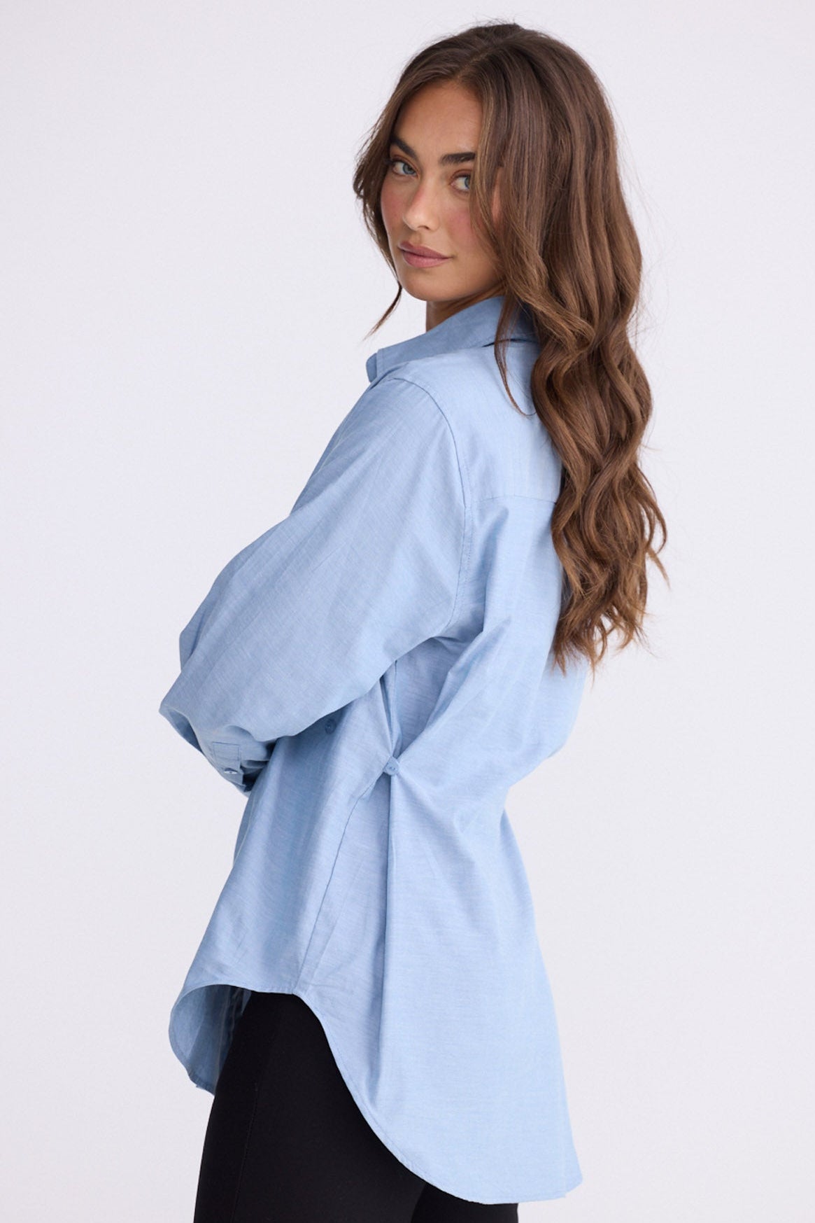 Model wearing Perry Shirt in blue with collar, side view on white background