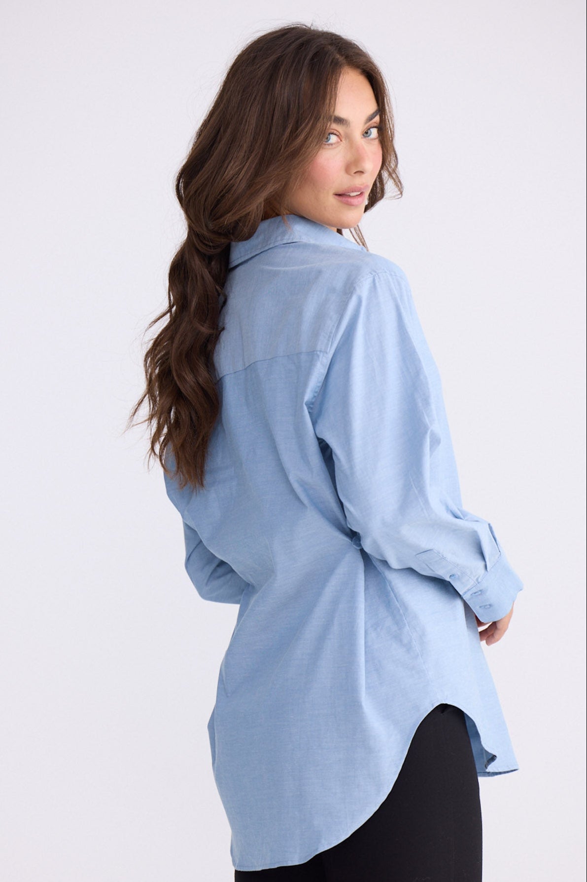 Model wearing Perry Shirt in blue with collar, back view on white background