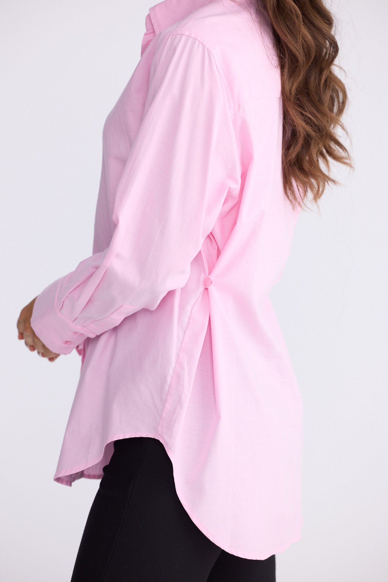 Model wearing Perry Shirt in pink with collar, side view on white background