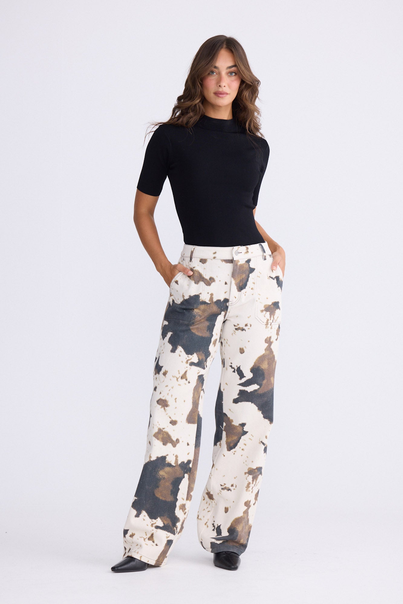 Model wearing Holstein Pant in abstract cow with cutaway pockets and straight-leg shape, back view on white background