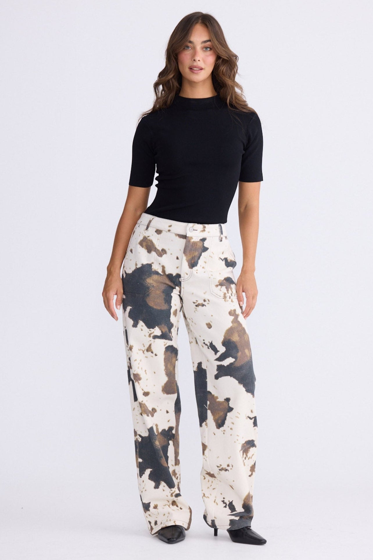 Model wearing Holstein Pant in abstract cow with cutaway pockets and straight-leg shape, front view on white background