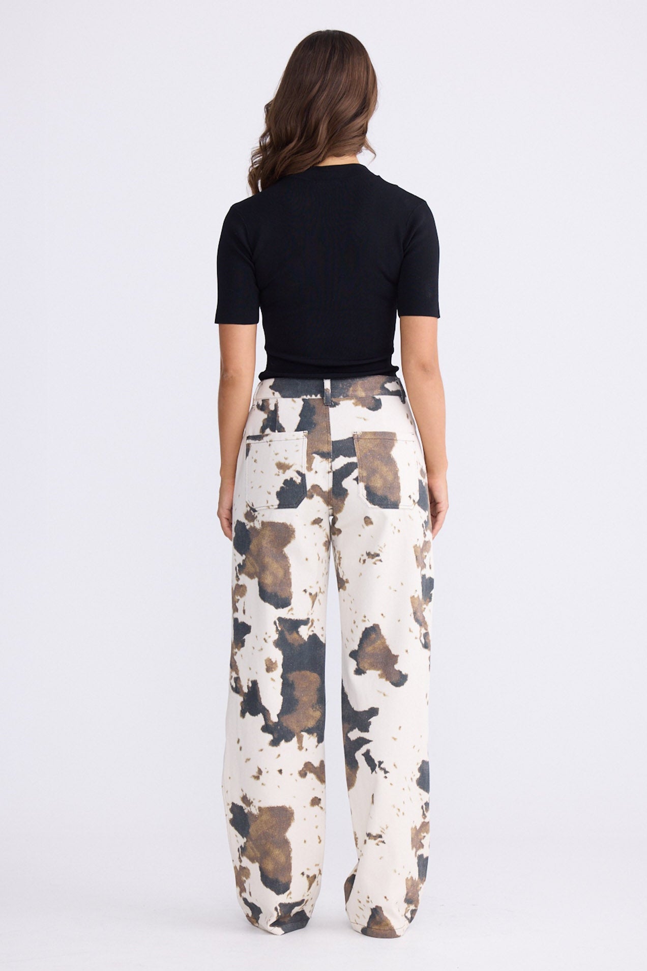 Model wearing Holstein Pant in abstract cow with cutaway pockets and straight-leg shape, front view on white background
